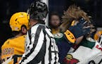 Minnesota Wild's Adam Beckman, right, gets a glove in the face from Nashville Predators' Dante Fabbro, left, during a scuffle in the first period of a