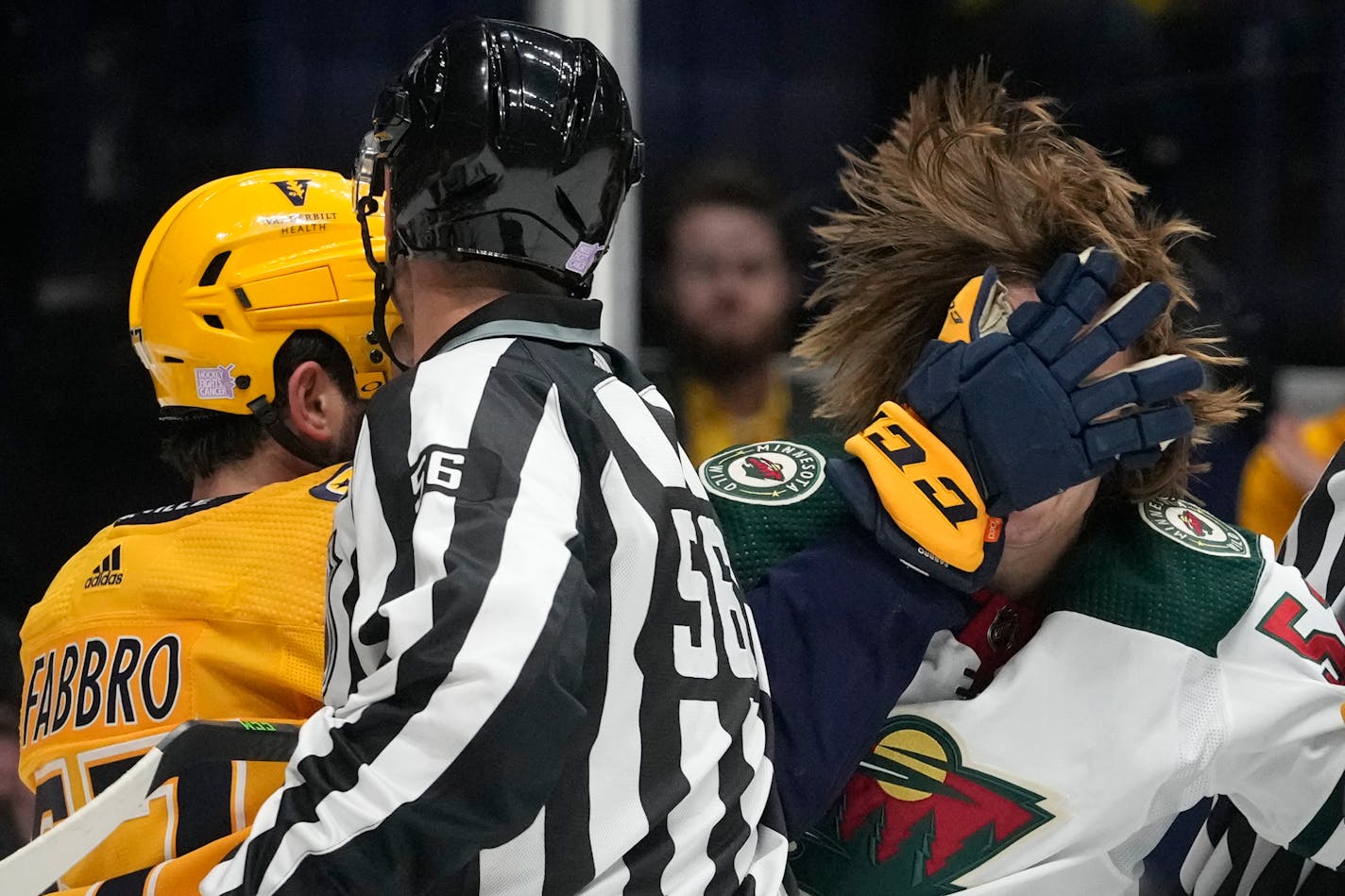 Minnesota Wild's Adam Beckman, right, gets a glove in the face from Nashville Predators' Dante Fabbro, left, during a scuffle in the first period of an NHL hockey game Tuesday, Nov. 15, 2022, in Nashville, Tenn. (AP Photo/Mark Humphrey)