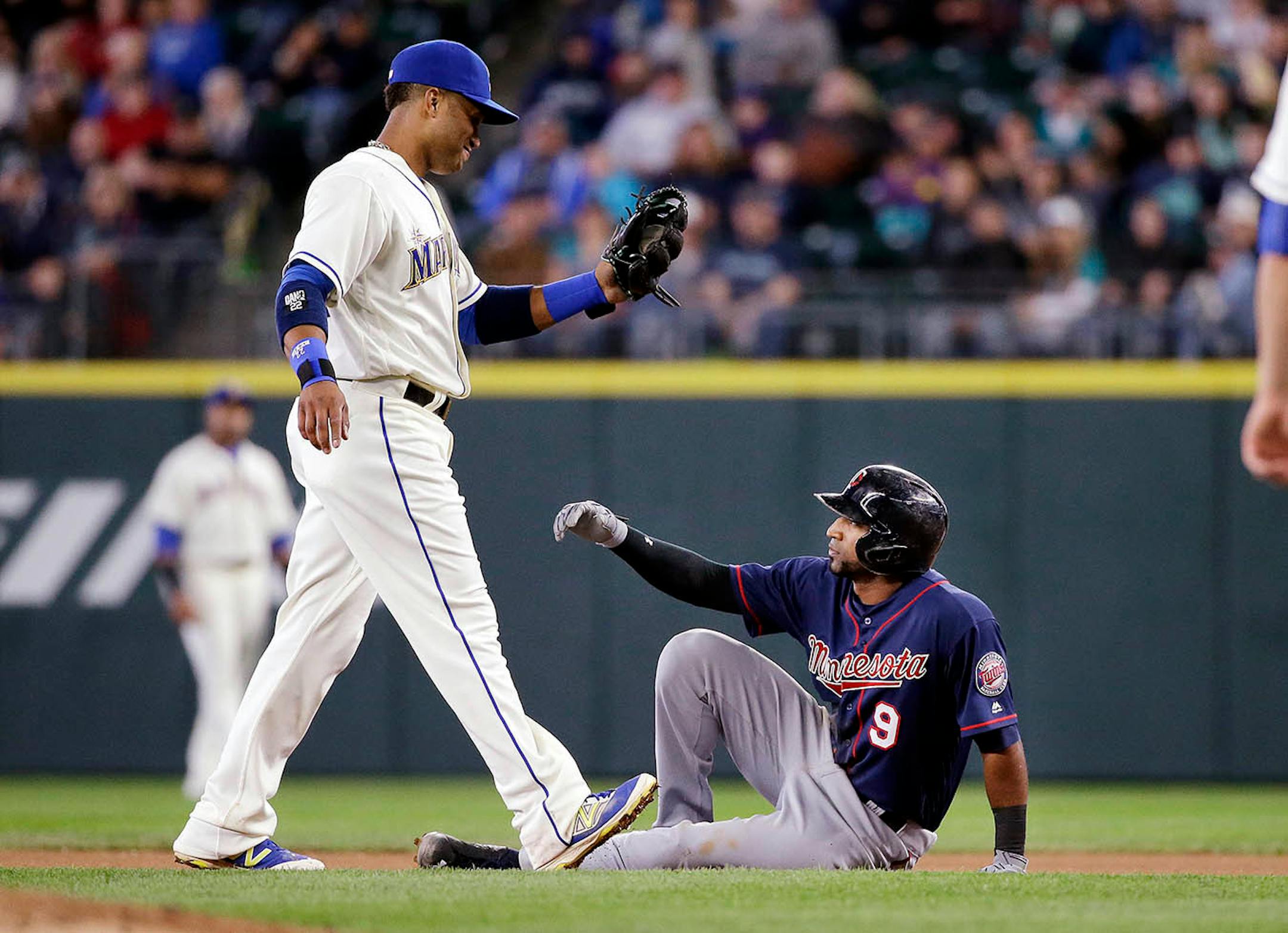 Minnesota Twins' Eduardo Nunez (9) sits and waits for Seattle Mariners second baseman Robinson Cano to tag him after Nunez slipped and fell after attempting to steal second base in the seventh inning of a baseball game Sunday, May 29, 2016, in Seattle.