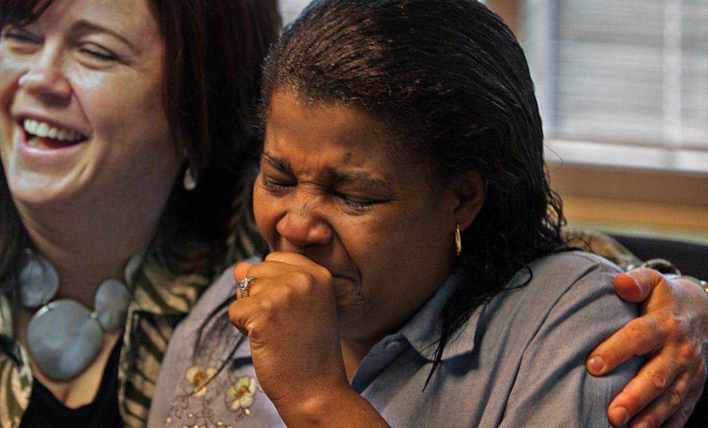 An emotional Leslie Parks (right) wept after she finished signing paper work associated with the purchase of a home in Minneapolis. Parks was locked out of her home a year and a half ago after a failed mortgage bank in California prematurely locked her out of her home while she and her mother were desperately negotiating to avert foreclosure. A group of local financial professionals heard what happened and came to her aid. At left is Liz Peter, a senior mortgage planner at Waterstone Mortgage Co