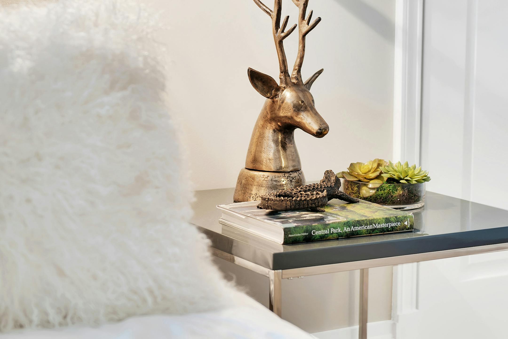 A bedside vignette using gold accents is mixed with organic elements such as succulents.