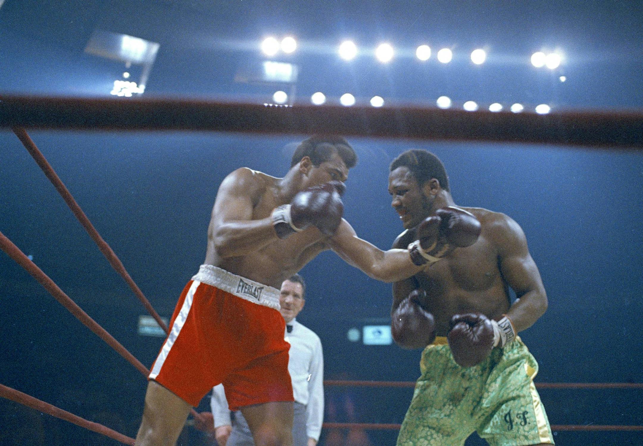 Muhammad Ali, red trunks, and Joe Frazier, green trunks, are shown during round 5 or 6 of their bout in New York's Madison Square Garden, March 8, 1971. Referee Arthur Mercante Sr. monitors closely in background. (AP Photo/John Lindsay) ORG XMIT: APHS455236