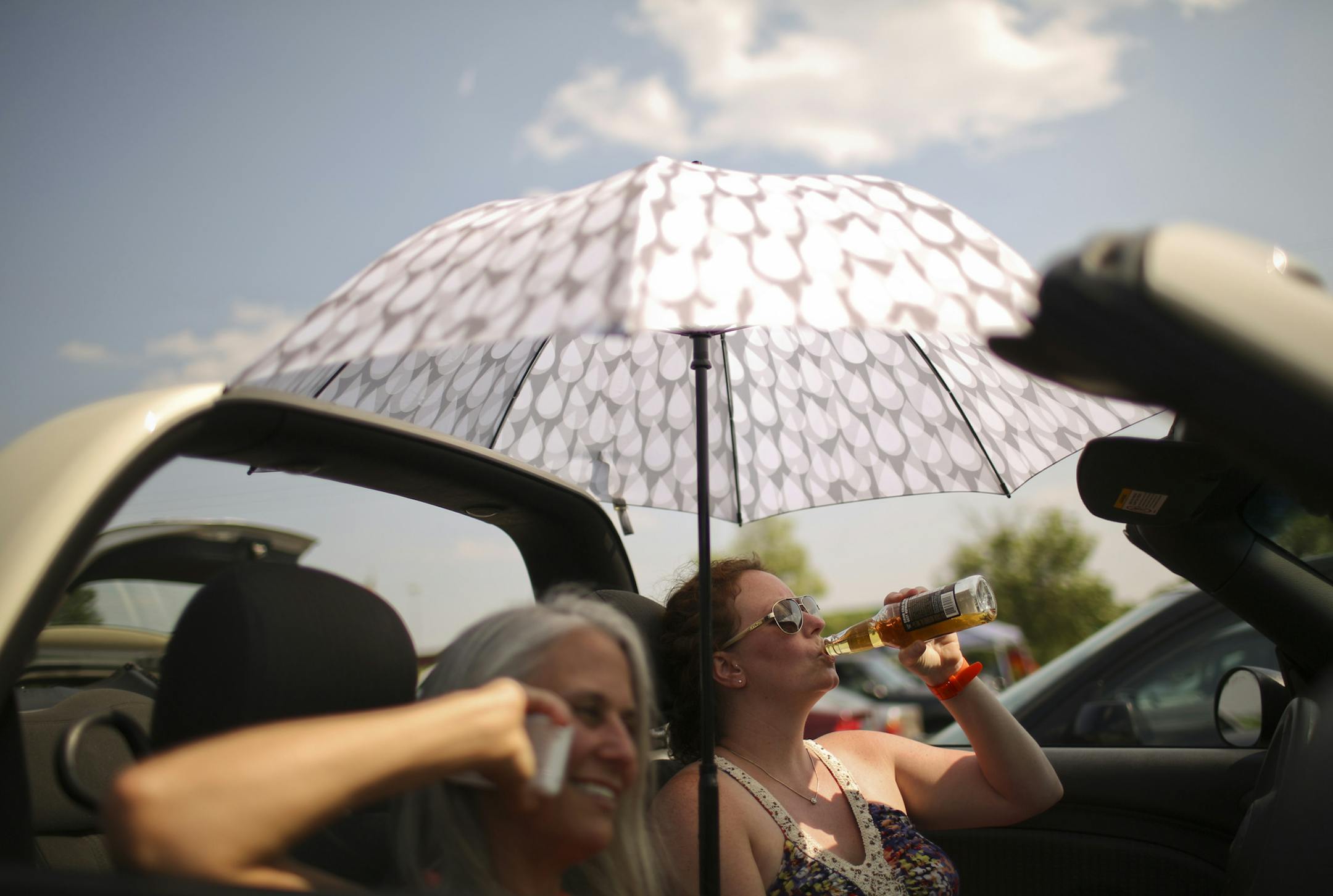 Bob Dylan and his Americanarama Festival of Music tour stopped at Midway Stadium in St. Paul, Minn. Wednesday night, July 10, 2013. Many early arrivers tailgated in the parking lot before going in to hear openers Richard Thompson, My Morning Jacket, Wilco, and eventually the night's headliner, the Bard of Hibbing. With the top down on her car and the umbrella up, Heather Mills of Maple Grove took a sip of hard cider while Kristina Schatz of St. Paul coordinated getting the ticket she left at hom