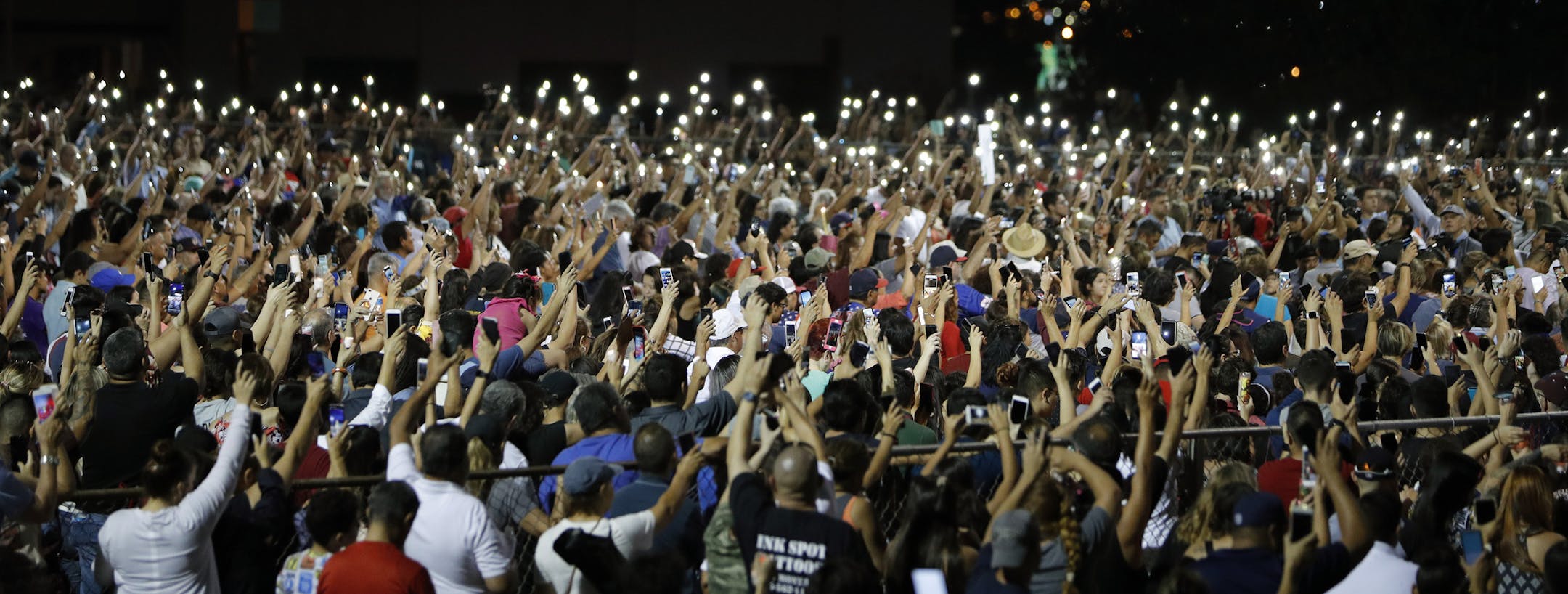 People raise their arms in the air during a vigil for victims of Saturday's mass shooting at a shopping complex Sunday, Aug. 4, 2019, in El Paso, Texas. (AP Photo/John Locher)