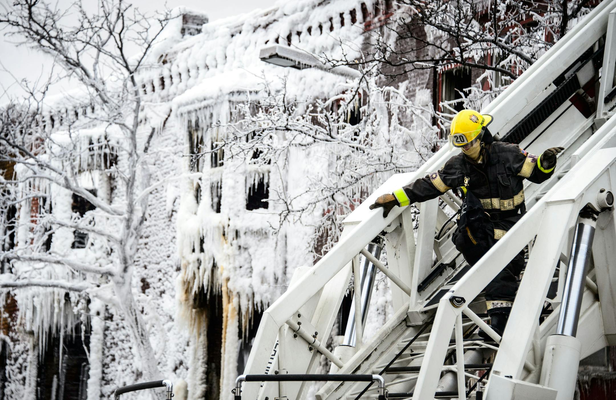 A Minneapolis firefighter came down from a ladder truck after spraying water on a building that burned Wednesday January 1, 2013 on Cedar Ave near 6th Ave. The frozen building shell is in the background. ] GLEN STUBBE * gstubbe@startribune.com
