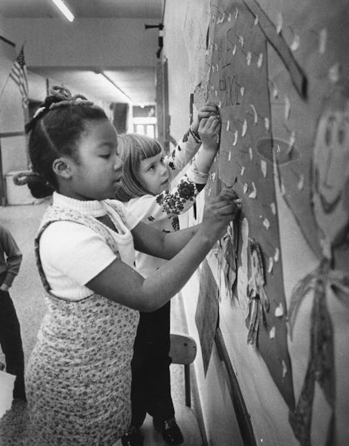 Star Tribune fileHale School had one black family before desegregation in 1971 paired it with heavily black Field School. Hale pupils Ann Mingo, 7, left, and Meg Lawson, 6, arranged a bulletin board in December 1971.