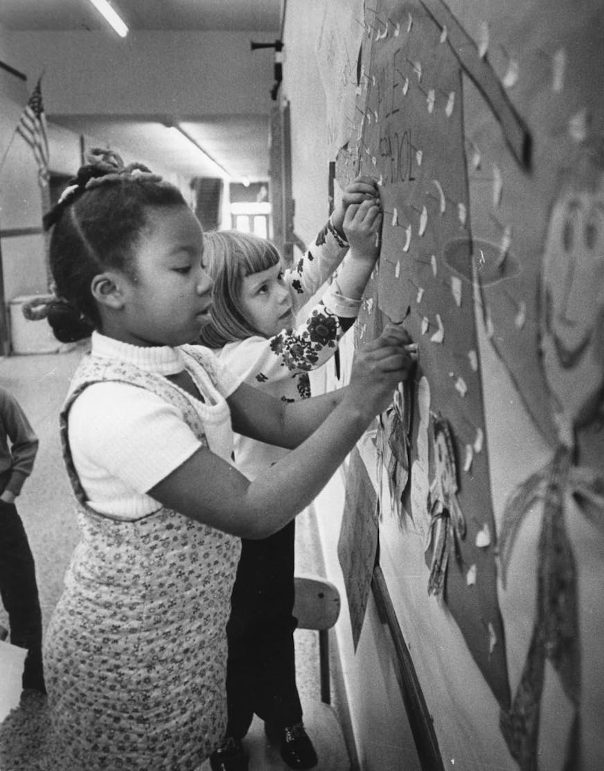 Star Tribune fileHale School had one black family before desegregation in 1971 paired it with heavily black Field School. Hale pupils Ann Mingo, 7, left, and Meg Lawson, 6, arranged a bulletin board in December 1971.