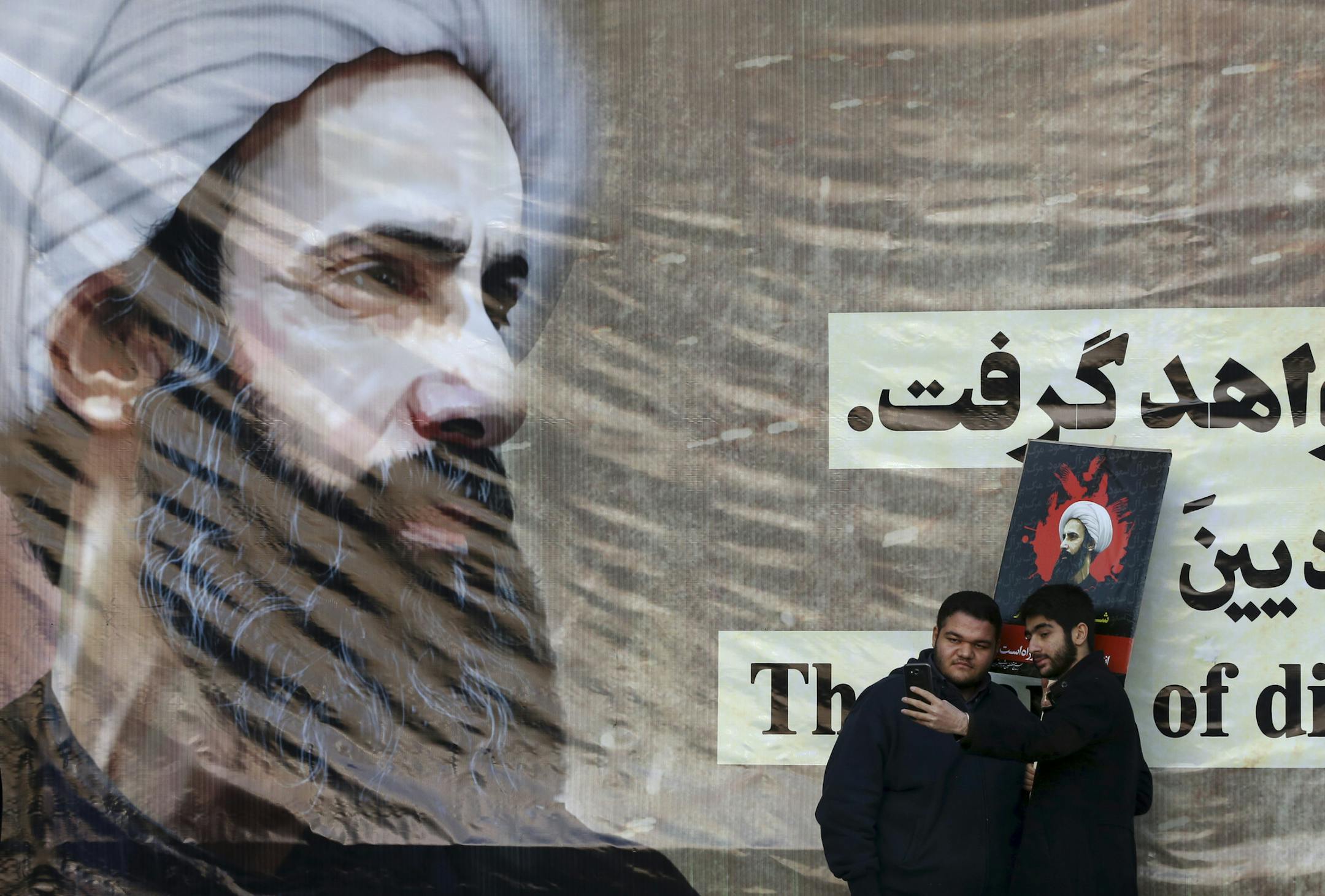 Iranian men take a selfie with a poster of Sheikh Nimr al-Nimr, a prominent opposition Saudi Shiite cleric, who was executed last week by Saudi Arabia, at the conclusion of a rally protesting his execution, in Tehran, Iran, Monday, Jan. 4, 2016. Allies of Saudi Arabia followed the kingdom's lead and began scaling back diplomatic ties to Iran on Monday after the ransacking of Saudi diplomatic missions in the Islamic Republic, violence sparked by the Saudi execution of al-Nimr. (AP Photo/Vahid Sal