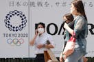People walk past an Tokyo Olympics logo in Tokyo, on June 25. 