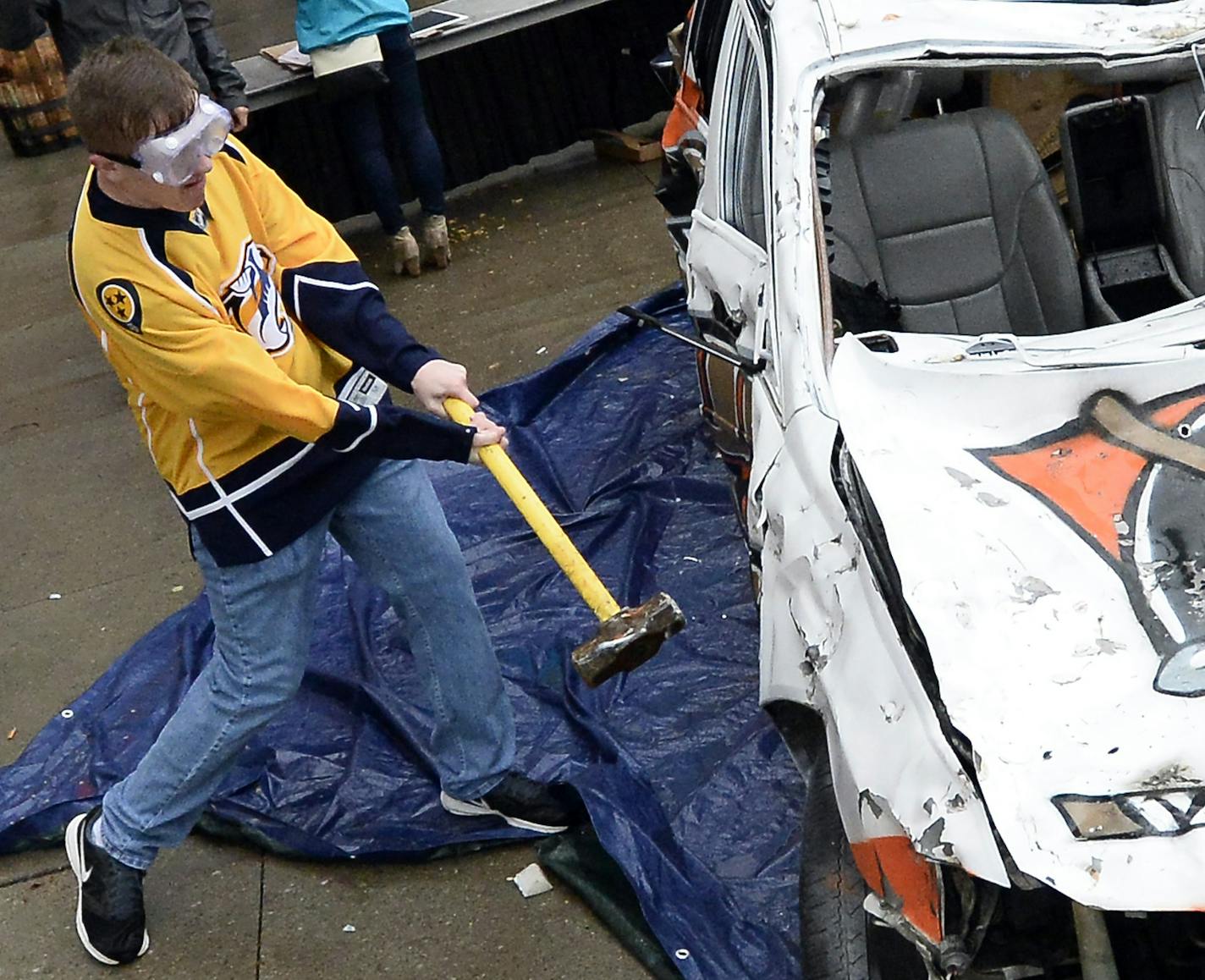 Nashville Predators fan, Colton Hager, 18, uses a sledgehammer as he takes a turn at beating a car painted with the Anaheim Ducks logo on it outside Bridgestone Arena before Game 4 in an NHL hockey first-round Stanley Cup playoff series Thursday, April 21, 2016, in Nashville, Tenn. (AP Photo/Mark Zaleski) ORG XMIT: OTK