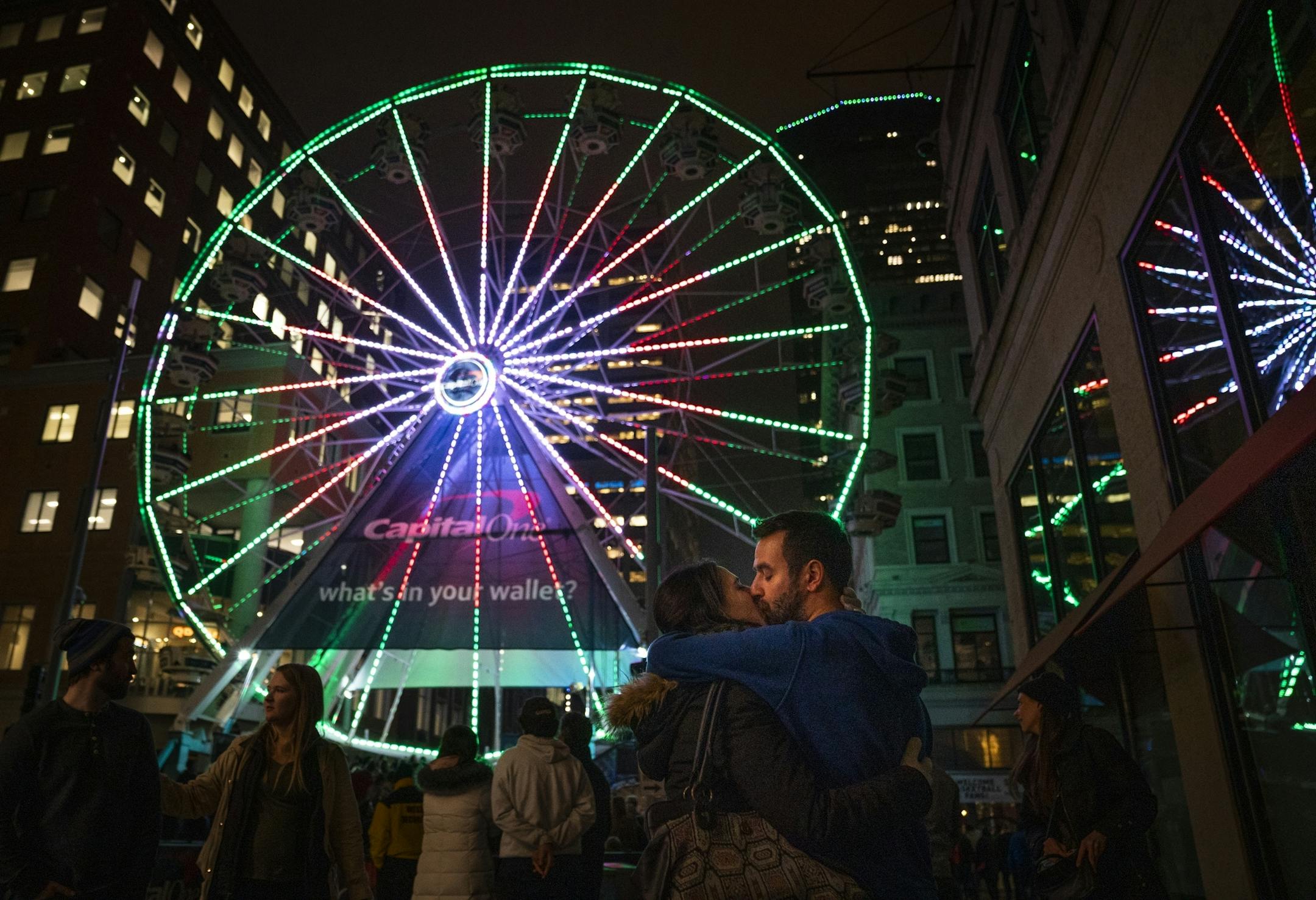 Carlos Abril and Almudena Andres, both visiting from Spain, share a kiss in front of the Ferris wheel Friday on Nicollet Mall during Tip-Off Tailgate.