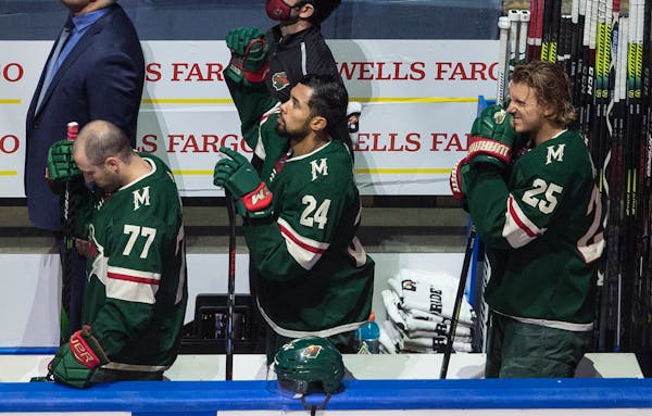 The Wild's Matt Dumba stands with fist raised during the national anthem before taking on the Canucks on Thursday night.