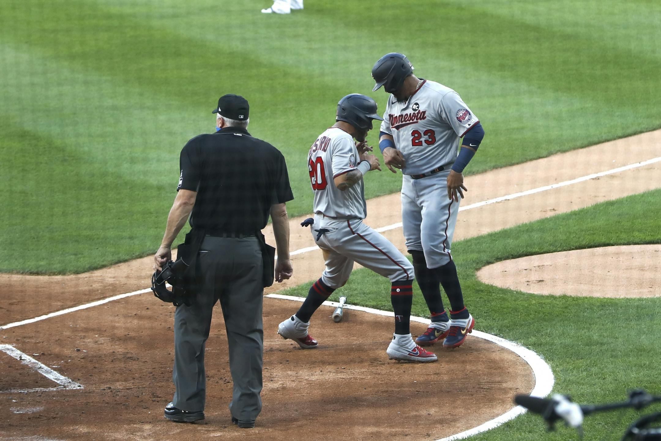 Minnesota Twins' Eddie Rosario (20) and Nelson Cruz celebrate after scoring on a single by Jake Cave off Chicago White Sox starting pitcher Lucas Giolito, during the first inning of a baseball game Friday, July 24, 2020, in Chicago.