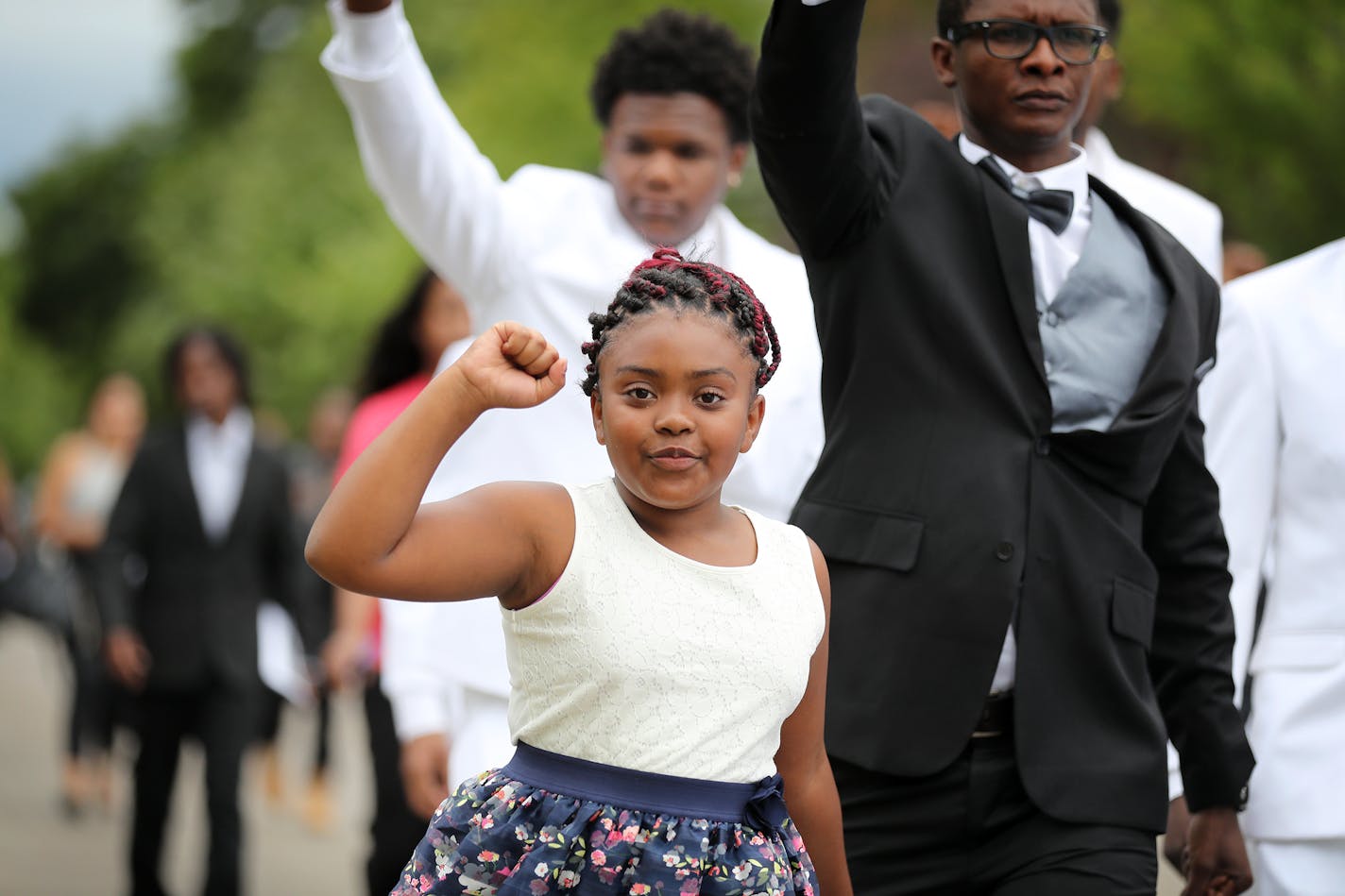 A girl raises her fist while walking in the funeral procession for Philando Castile.