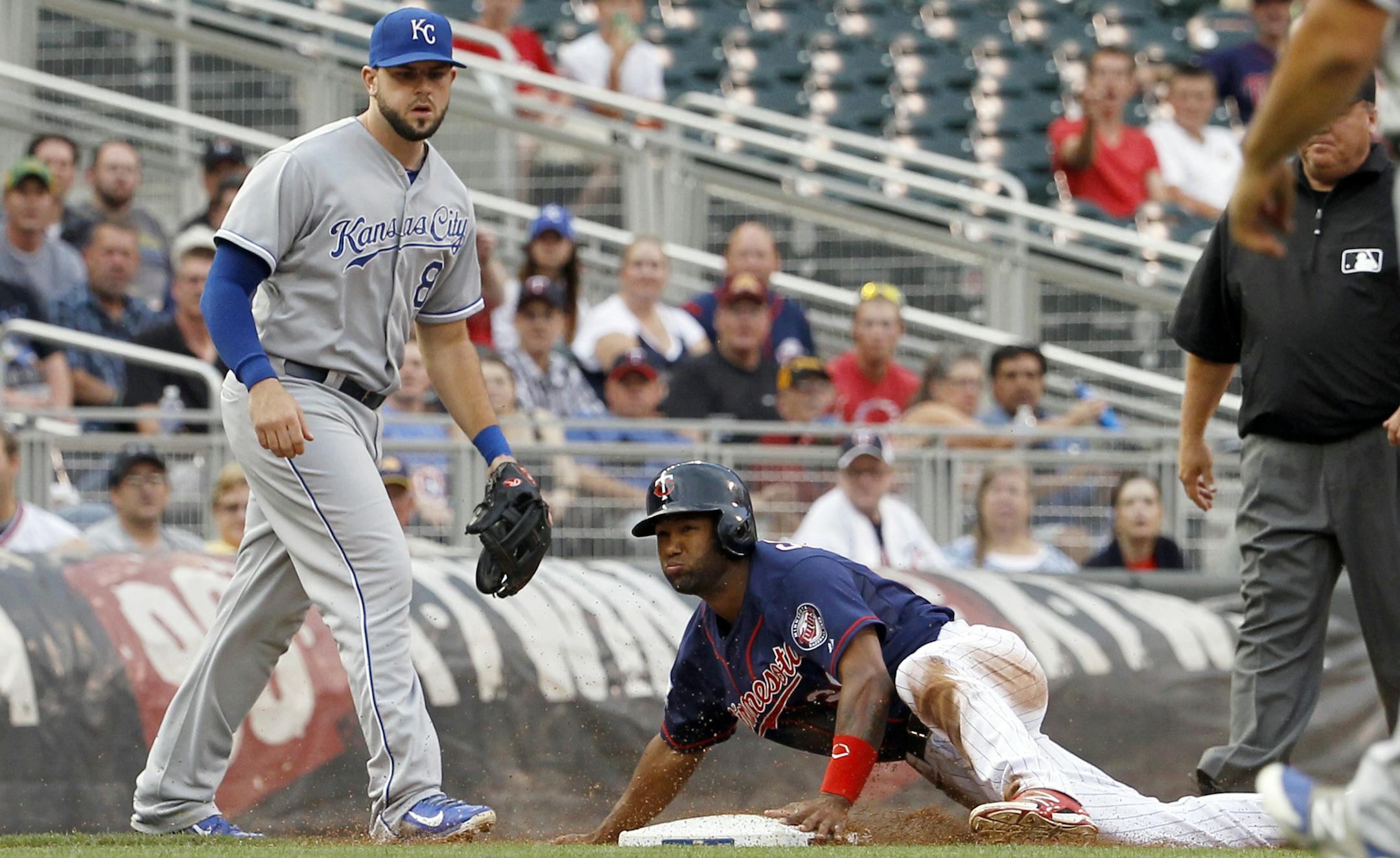 Minnesota Twins' Danny Santana, right, safely steals third base as Kansas City Royals third baseman Mike Moustakas, left, covers third during the first inning of a baseball game in Minneapolis, Monday, Aug. 18, 2014. (AP Photo/Ann Heisenfelt)