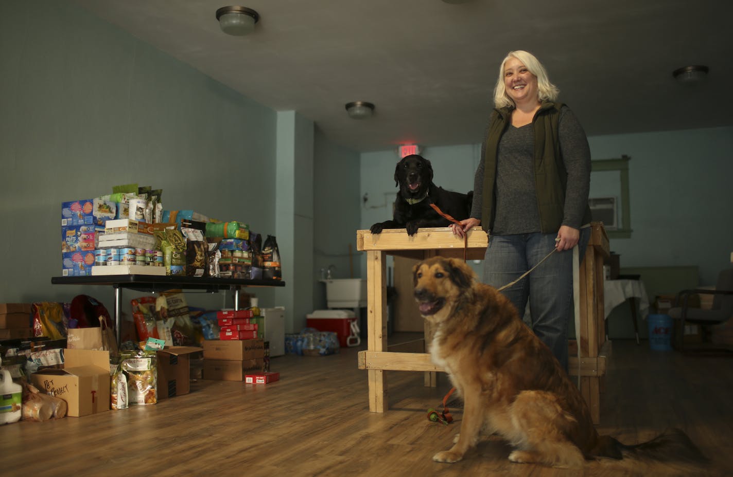 Kim Carrier with her two dogs, Rosie (on the table) and Stella, at People & Pets Together, which will be the state's first dedicated food shelf for pets when it opens, she hopes, by the end of the year. The pet food at left was all donated during an open house last weekend. ] JEFF WHEELER &#xef; jeff.wheeler@startribune.com In the height of the Great Recession, Kim Carrier and a band of dedicated volunteers started stocking food shelves with pet food, with the idea that that hungry people should