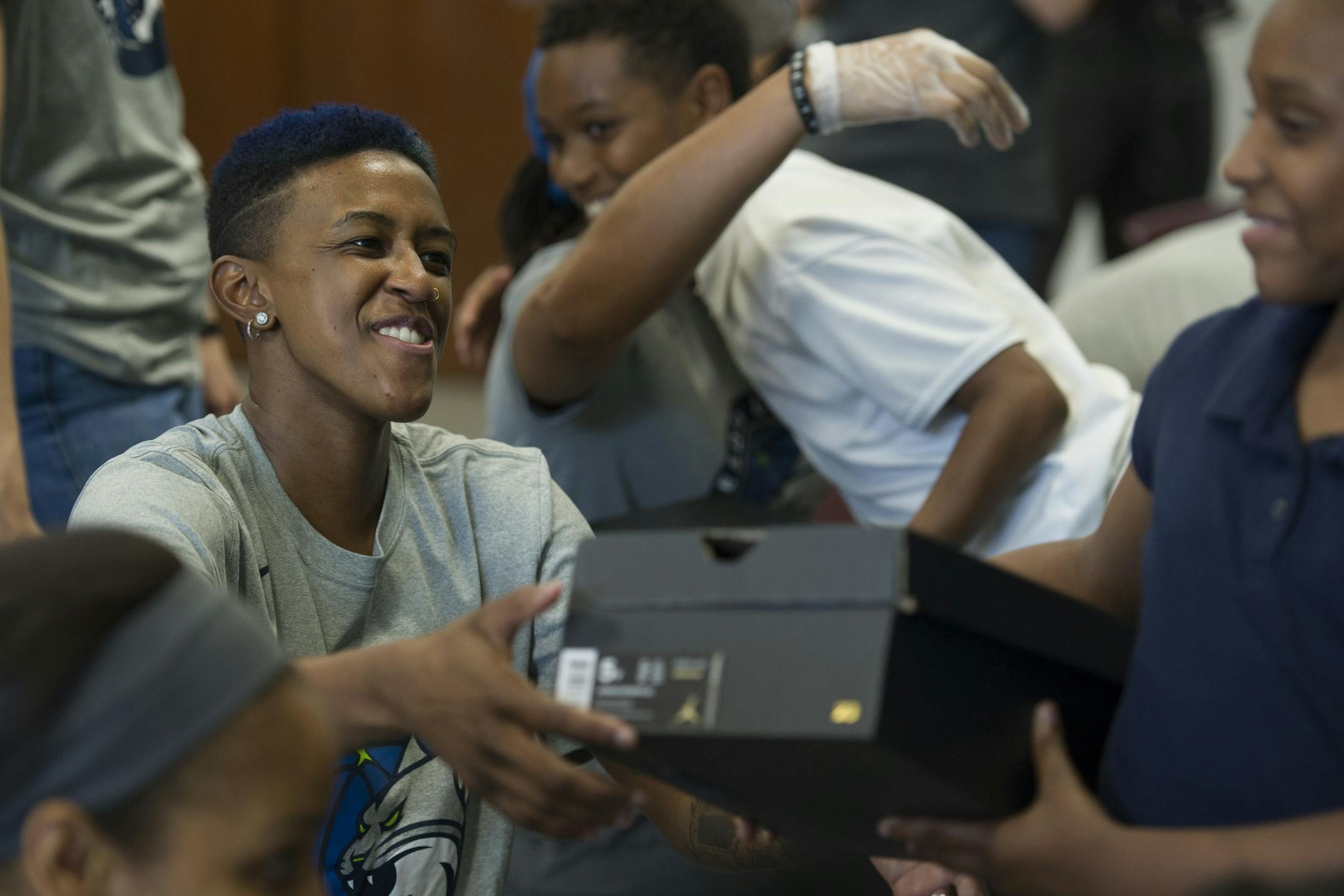 WNBA Champion Minnesota Lynx guard Danielle Robinson hands a student a Nike box containing his old shoes after washing his feet and tying on a new pair of Nike Jordan shoes at Payne Elementary School in Washington, Wednesday, June 6, 2018. Payne Elementary has the highest homeless student population in the district.