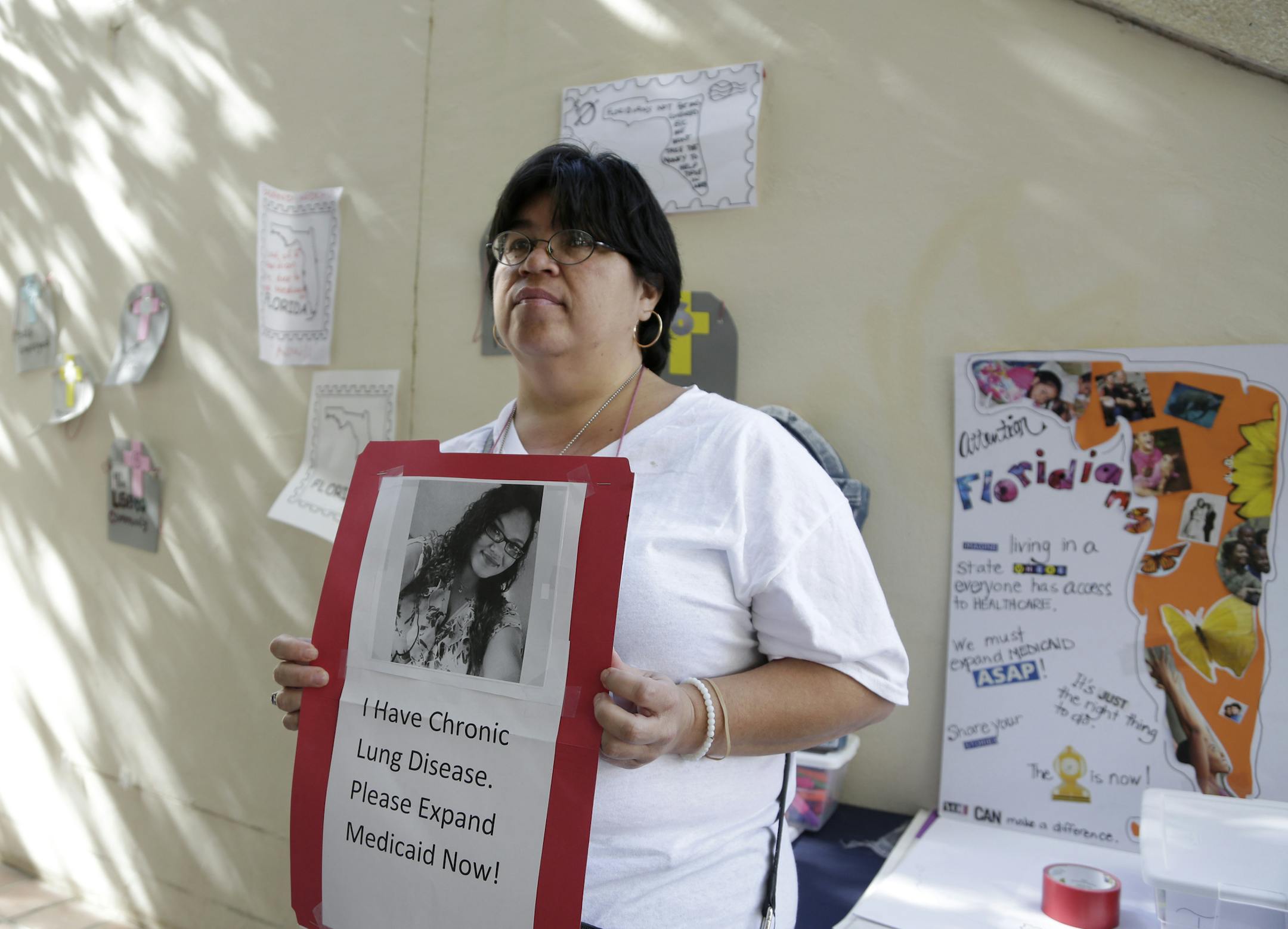 Mariamee Rodriguez holds a photo of her daughter Genesis Matos Rodriguez, 20, who has chronic lung disease during a protest in support of Florida lawmakers expanding eligibility for Medicaid as called for under the Affordable Care Act, Thursday, Jan. 8, 2015, in Miami. Rodriguez works part time, but does not have health care coverage for herself or daughter. The Supreme Court ruled in 2012 that Medicaid expansion is an optional part of the Affordable Care Act. (AP Photo/Lynne Sladky)
