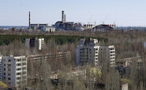 The town of Prypyat is seen against the background of the damaged reactor at the Chernobyl nuclear power plant in Prypyat, Ukraine, Tuesday, April 23,