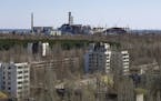 The town of Prypyat is seen against the background of the damaged reactor at the Chernobyl nuclear power plant in Prypyat, Ukraine, Tuesday, April 23,