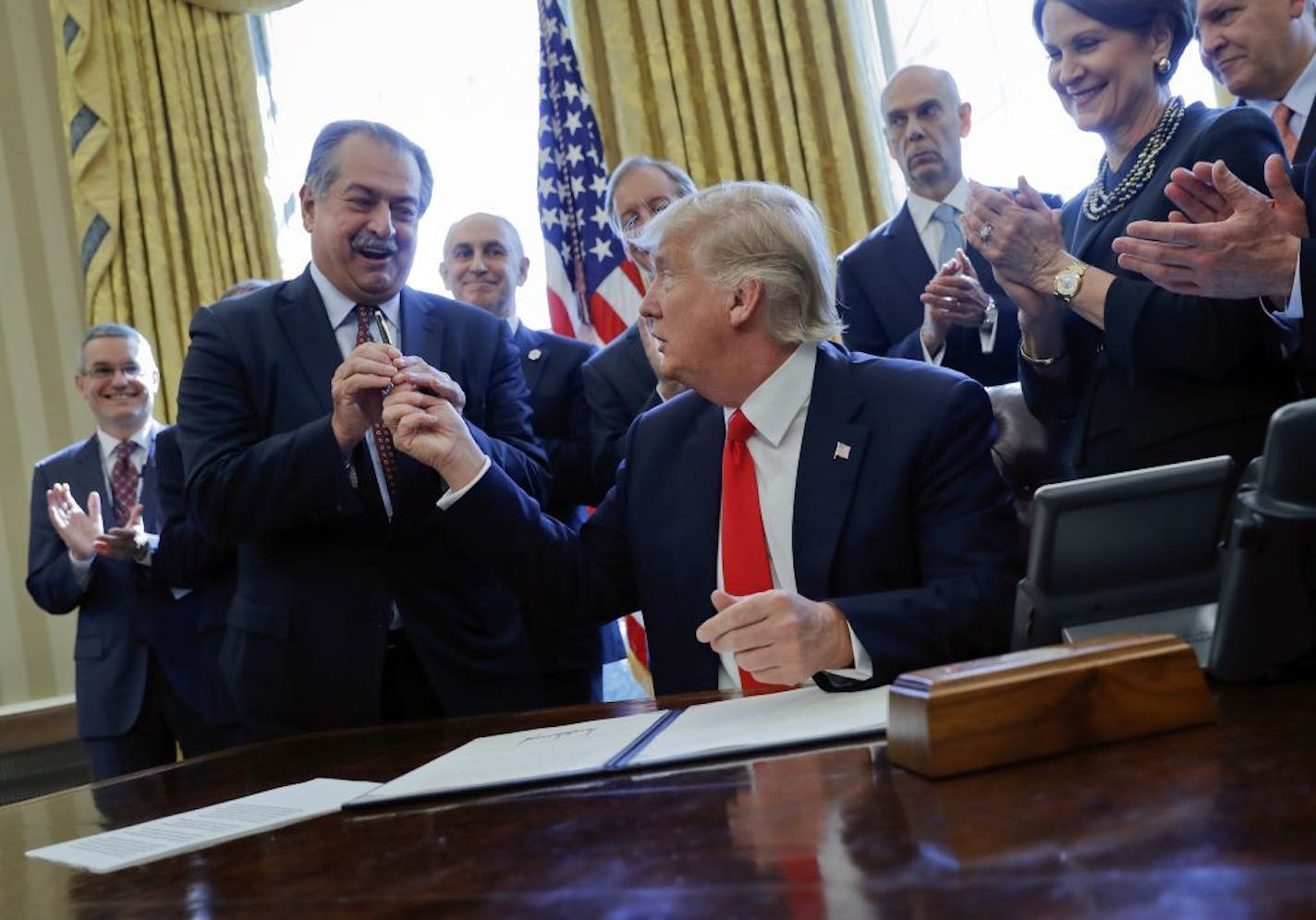 FILE - In this Feb. 24, 2017, file photo, President Donald Trump gives the pen he used to sign an executive order to Dow Chemical President, Chairman and CEO Andrew Liveris, as other business leaders applaud in the Oval Office of the White House in Washington. Environmental Protection Agency Administrator Scott Pruitt's schedule shows he met with Dow CEO Andrew Liveris for about a half hour on March 9 during a conference held at a Houston hotel. Twenty days later Pruitt announced his decision to