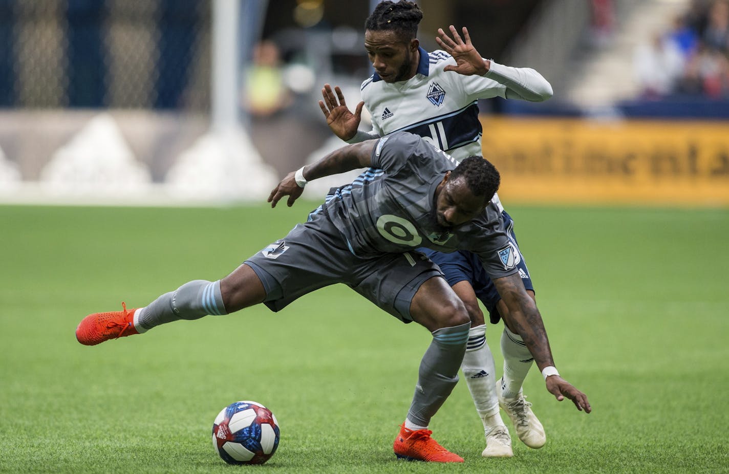 Vancouver Whitecaps' Alhassane Bangoura, rear, plays the ball against Minnesota United's Romain Metanire during the second half of an MLS soccer match Saturday, March 2, 2019, in Vancouver, British Columbia. (Ben Nelms/The Canadian Press via AP)