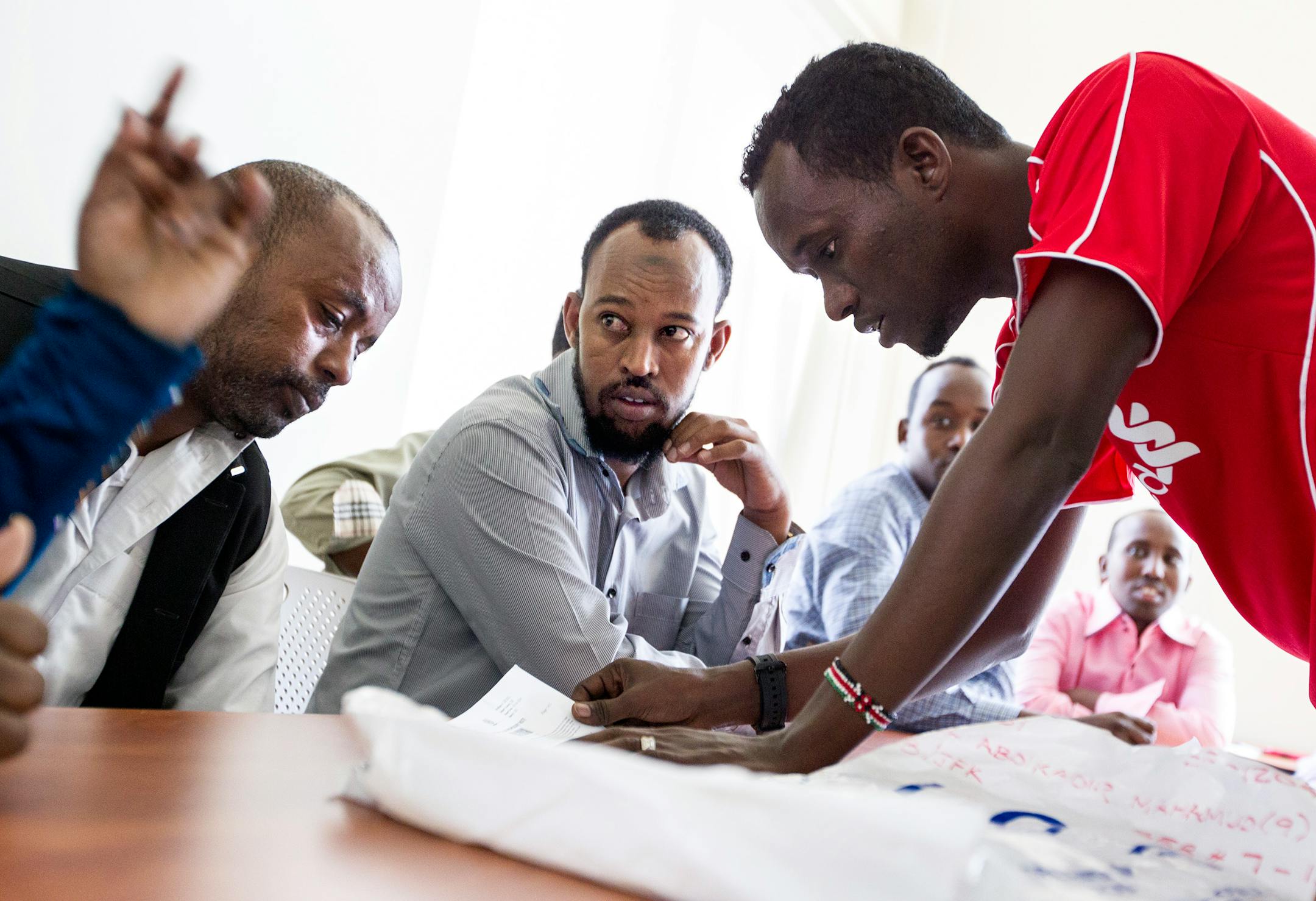 Volunteer Mohamed Ali Mohamed, right, answers questions for new Somali refugees Abdikadir Mohamud Ismail, left, and Burhan Hussein Abdi, center, during a Cultural Orientation class for new Somali refugees at Lutheran Social Service of Minnesota in Minneapolis.