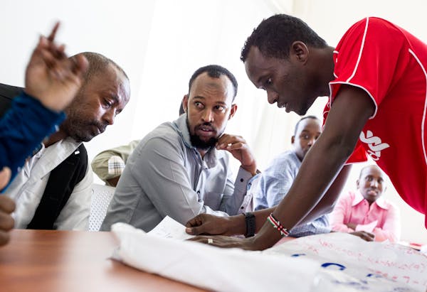 Volunteer Mohamed Ali Mohamed, right, answers questions for new Somali refugees Abdikadir Mohamud Ismail, left, and Burhan Hussein Abdi, center, durin