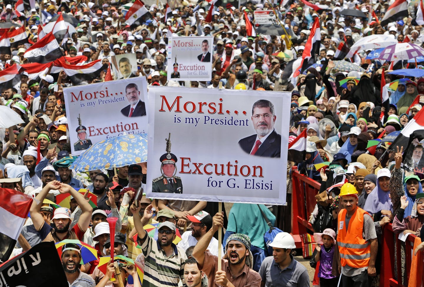 Supporters of Egypt's ousted President Mohammed Morsi hold up placards as they shout slogans during a demonstration where protesters have installed their camp, at Nasr City, Cairo, Egypt, Friday, July 19, 2013. Thousands of protesters are holding rallies across Egypt to demand the reinstatement of ousted President Mohammed Morsi. The Muslim Brotherhood, from which Morsi hails, is mobilizing followers to march in Cairo and elsewhere Friday for a protest they�re dubbing "Breaking the Coup.�