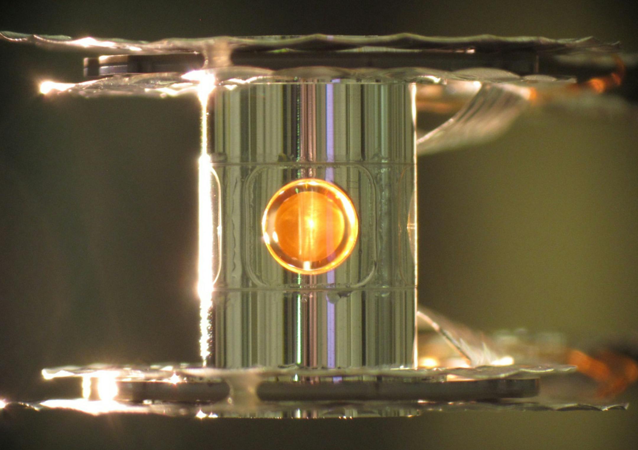 This undated image provided by the Lawrence Livermore National Laboratory shows a deuterium and tritium capsule, sphere in window at center, inside a cylindrical hohlraum container about 0.4 inches tall. In research reported Wednesday, Feb. 12, 2014 by the journal Nature, scientists say they've taken a key step toward harnessing nuclear fusion as a new way to generate power, an idea that has been pursued for decades. In tests, 192 laser beams briefly fired into the small gold cylinder which held