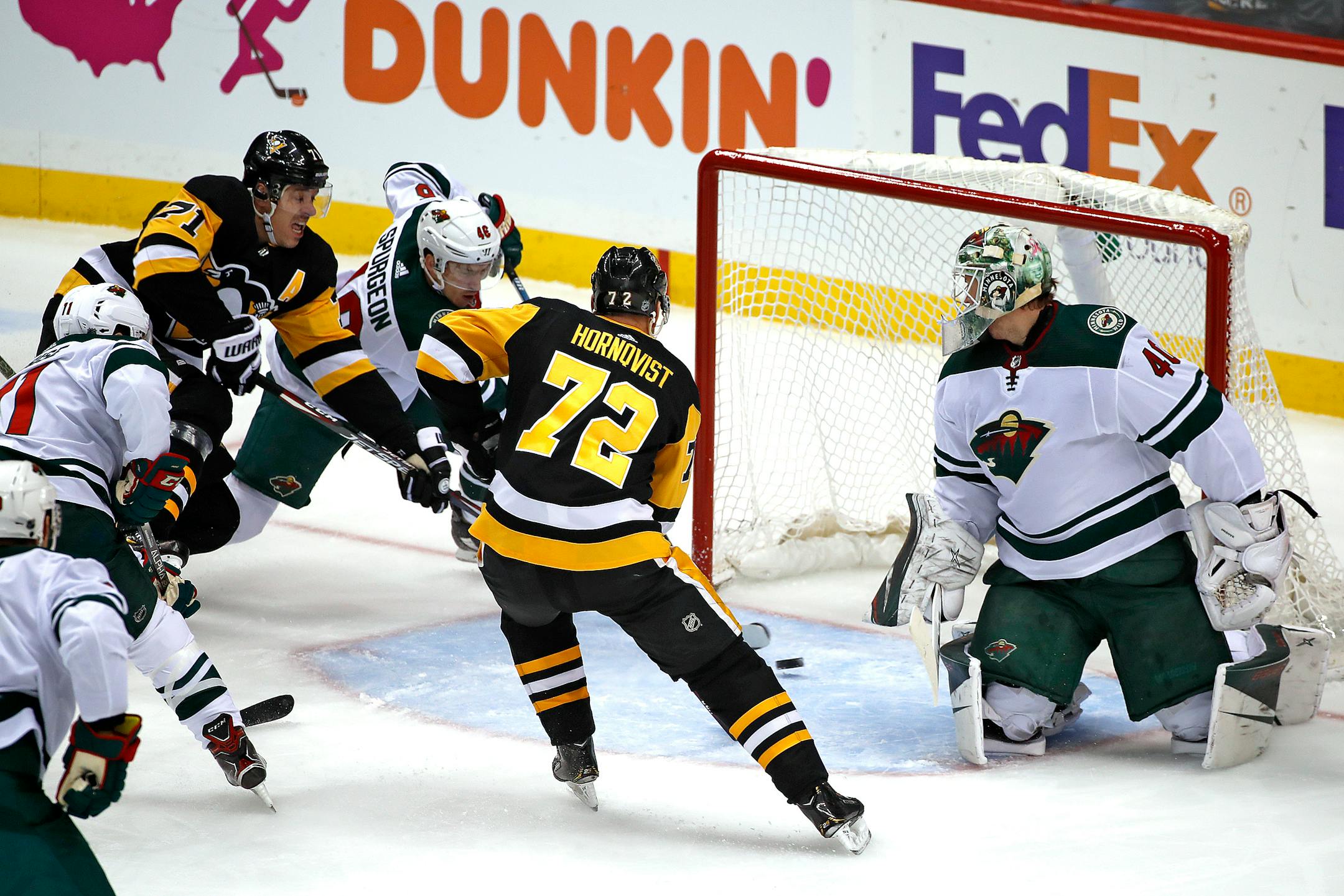 Pittsburgh's Evgeni Malkin (71) puts the puck behind Wild goaltender Devan Dubnyk with Jared Spurgeon defending for a goal during the first period