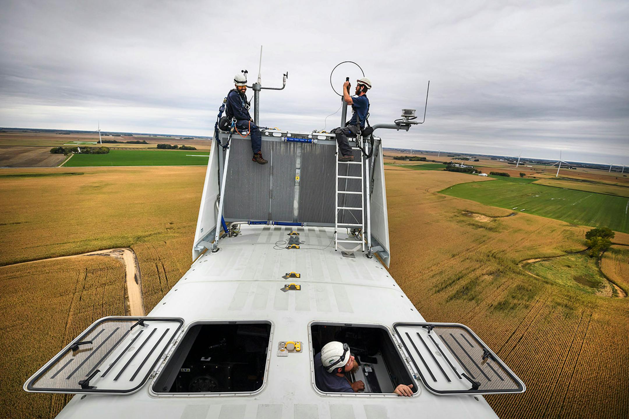 Outside the nacelle of a Vestas wind turbine, 300 feet in the air, Will Osborn, left and Shane Keck serviced a wind sensor that was out of alignment while Chris Berg worked inside.