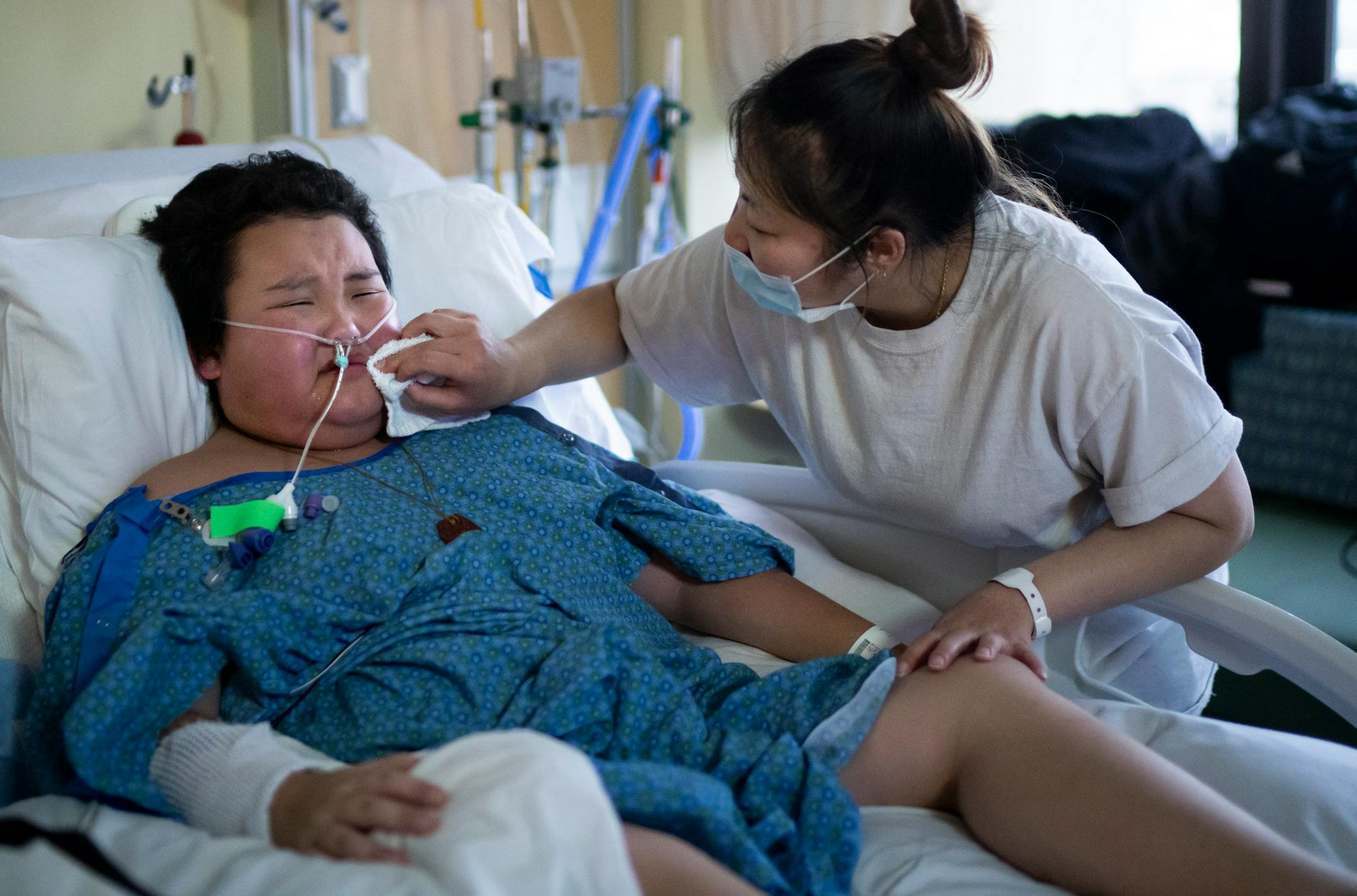 Troy Chang, 9, cries in his hospital bed while recovering from COVID-19 and only being extubated two days earlier as his mom Linda Vang wipes away his tears at HCMC on Friday, Jan. 7, 2022 in Minneapolis, Minn. He has been in the hospital since Dec. 14 and became emotional talking about how he wants to go home.
