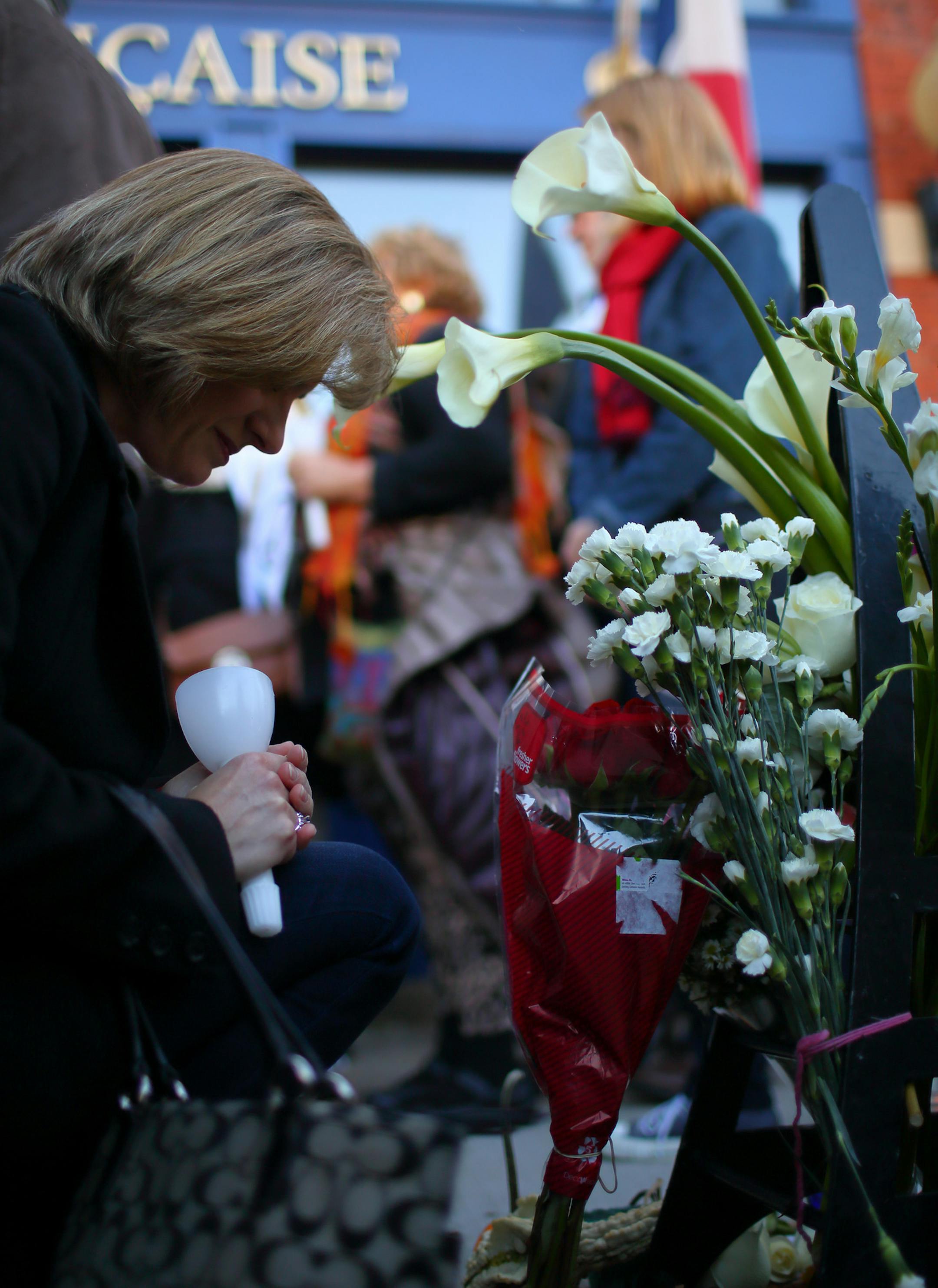 A woman prayed briefly at a memorial outside the Alliance FranÁaise after leaving a bouquet of flowers before the march began Sunday afternoon.