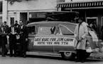 A hearse with a casket mounted on its top and a sign reading: Last Ride For Jim Crow, is parked in front of headquarters for workers favoring approval
