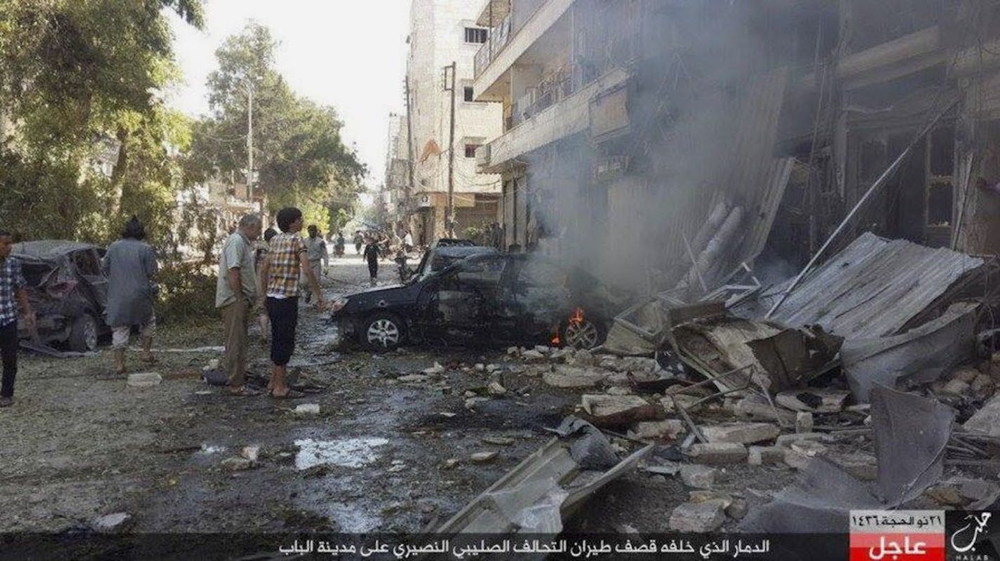 In this Monday, Oct. 5, 2015 photo released by the Rased News Network, a Facebook account affiliated with Islamic State militants, which has been authenticated based on its contents and other AP reporting, people gather at the site of an airstrike in Al-Bab on the outskirts of Aleppo, Syria. The Britain-based Syrian Observatory for Human rights said warplanes believed to be Russian have targeted the northern town of Al-Bab that is a stronghold of the Islamic State group. The Arabic at the bottom