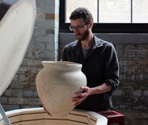 Ceramic artist Mitch Iburg uses eco-friendly techniques in making his clay pots and sculptures, including this vessel that he is unloading from an oxi