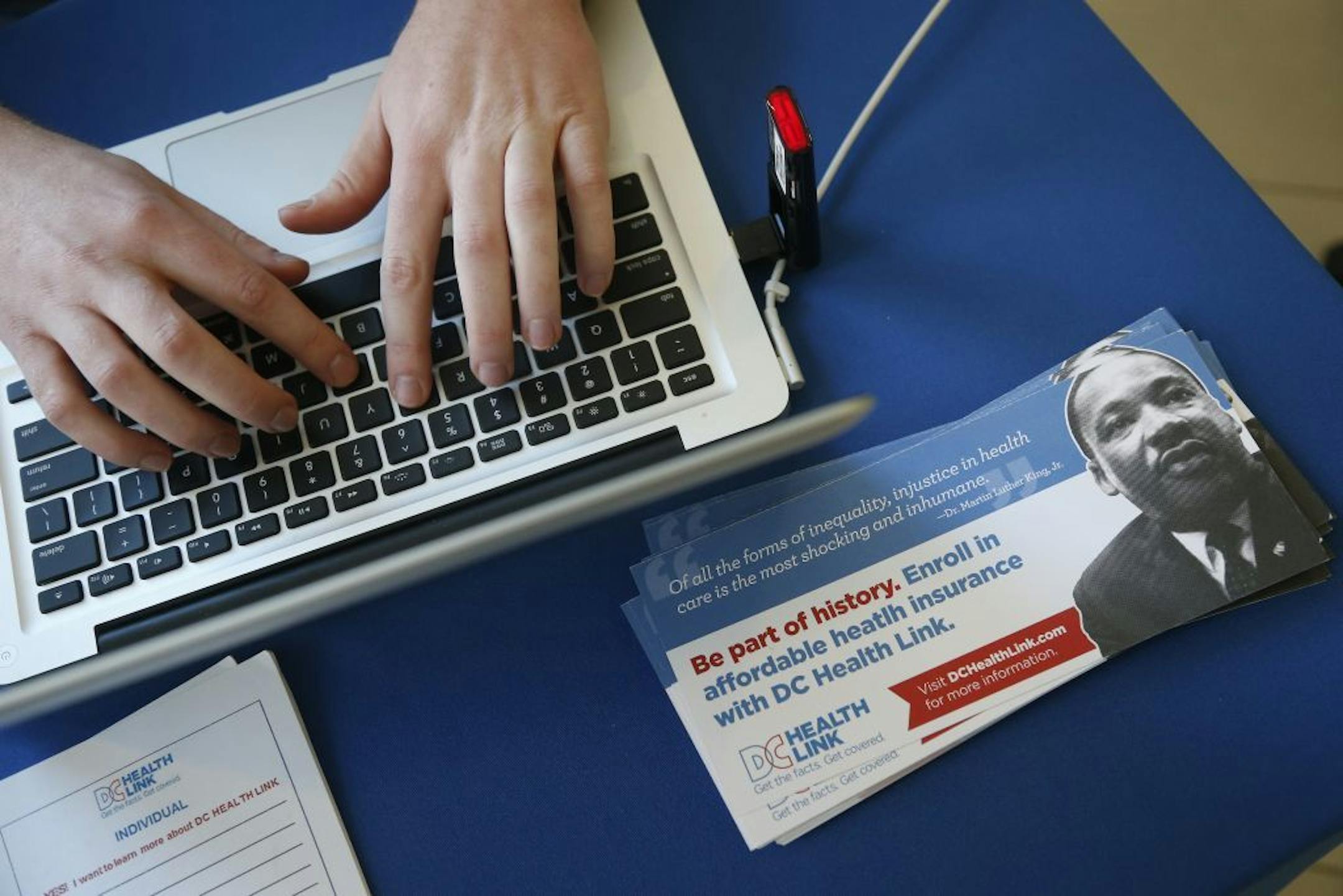 David Bransfield, a state outreach coordinator for Young Invincibles, a group which supports President Barack Obama's health care law, works on his computer at a table set up to sign people up for health care at the University of the District of Columbia in Washington, Thursday, Jan. 30, 2014. An army of workers and volunteers has fanned out around the country trying to enroll young and healthy people in health insurance now available through Obama�s signature law.