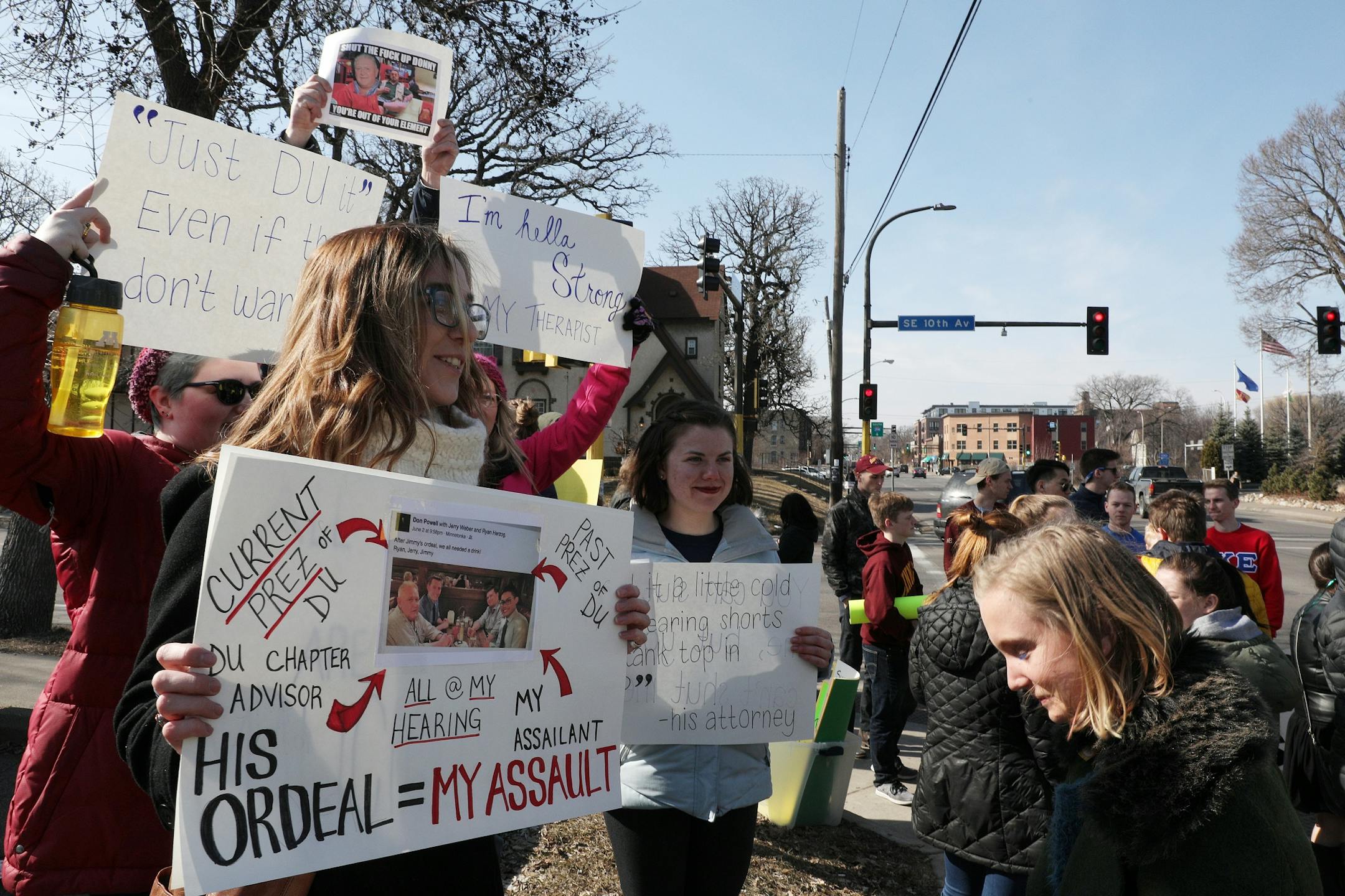 Kayla Pederson, left, stood with a sign identifying her assailant Saturday.