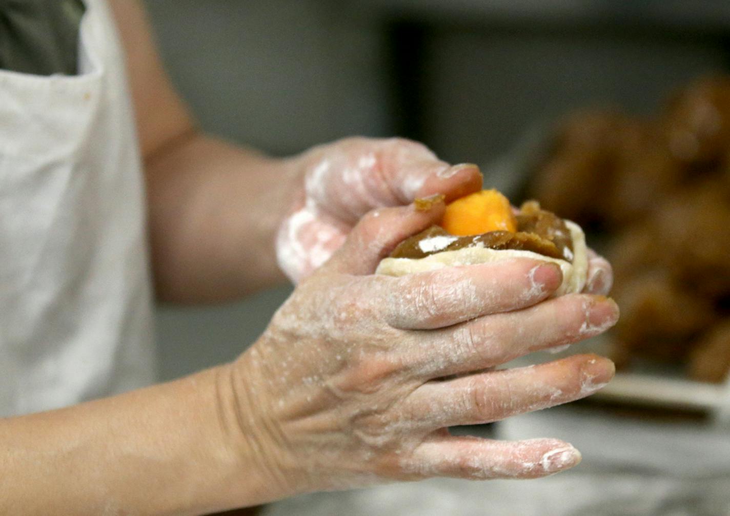 Pauline Kwan made mooncakes ahead of the lunar calendar harvest holiday that begins on Monday. Mooncakes are a specialty at the Mid-Autumn Festival and this is one of the only places in the Twin Cities where they are made. Here, Kwan, who has been making mooncakes for 35 years, fashions dough around an egg yolk and filling before placing in a wooden mold to form a moonlike before baking and seen Wednesday, Sept. 18, 2018, in Minneapolis, MN.] DAVID JOLES • david.joles@startribune.com Michelle Kw