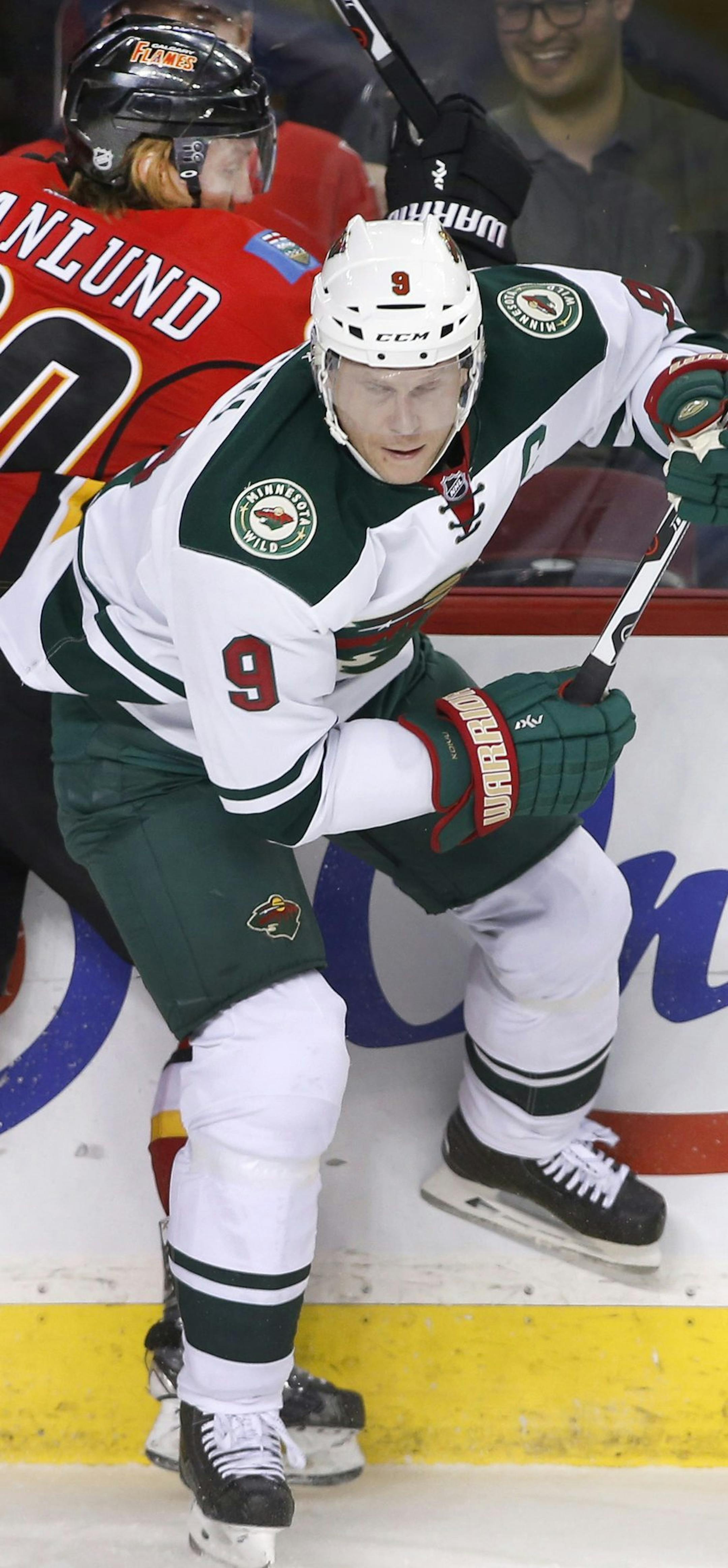 Minnesota Wild's Mikko Koivu (9), from Finland, is checked by Calgary Flames' Markus Granlund, from Finland, during the first period of an NHL hockey game Wednesday, Feb. 17, 2016, in Calgary, Alberta. (Larry MacDougal/The Canadian Press via AP)