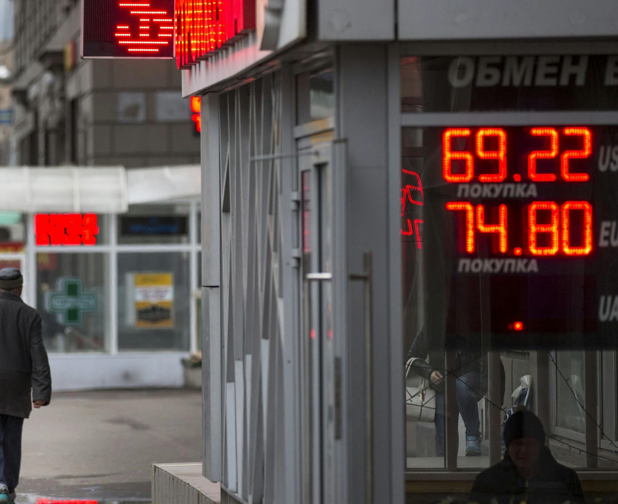 People walk past an exchange office sign showing the currency exchange rates of Russian ruble, U.S. dollar, and euro in Moscow, Russia, Tuesday, Dec. 8, 2015. The ruble continued to decline on Tuesday as oil prices are reaching a seven-year low. (AP Photo/Alexander Zemlianichenko)