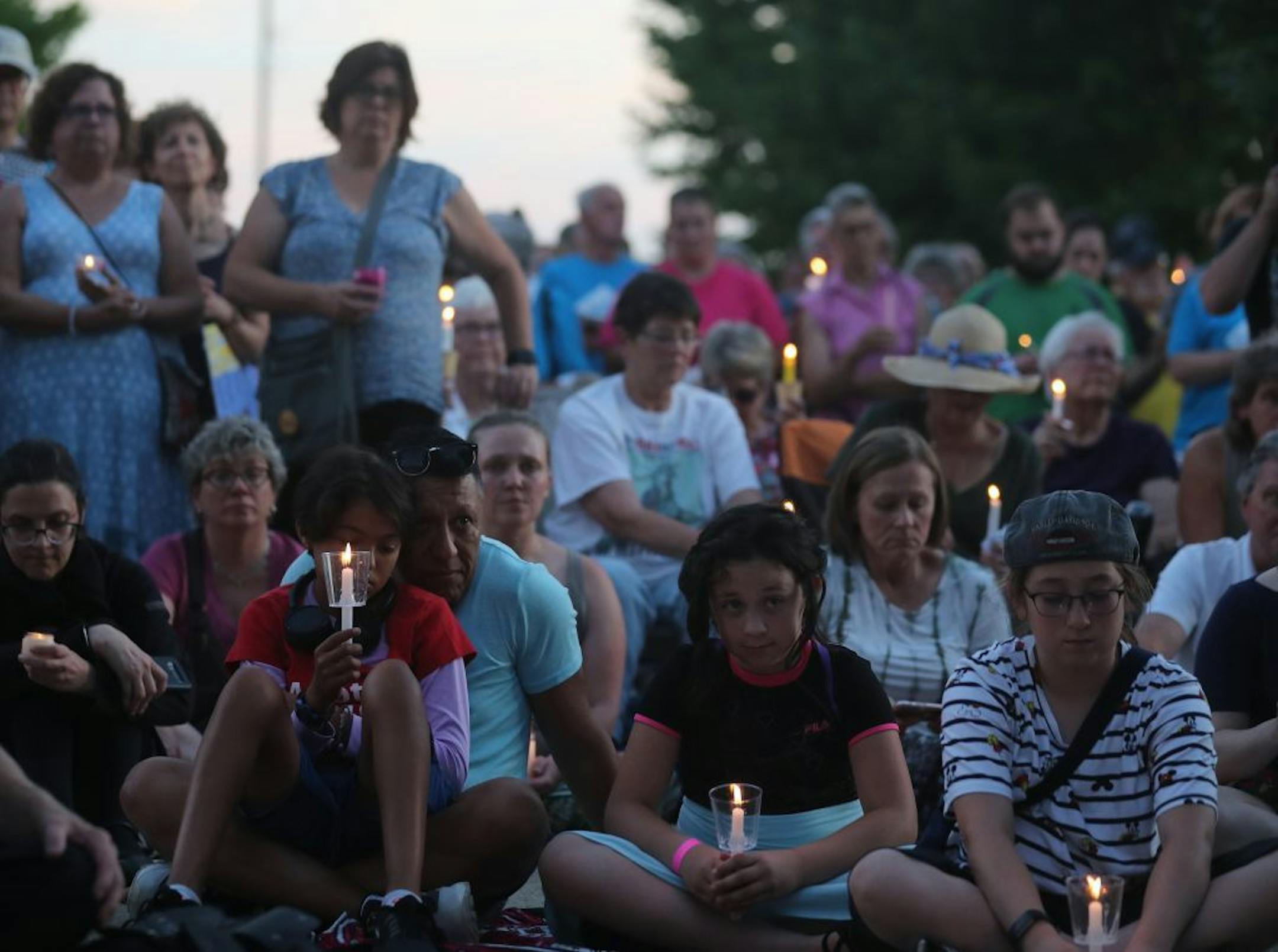 Ruben Vazquez of New Brighton, front left, sat with daughter Jasmine Vazquez-Matze, 12, during a moment of silence during a vigil outside Whipple Federal Building on Friday at Fort Snelling.