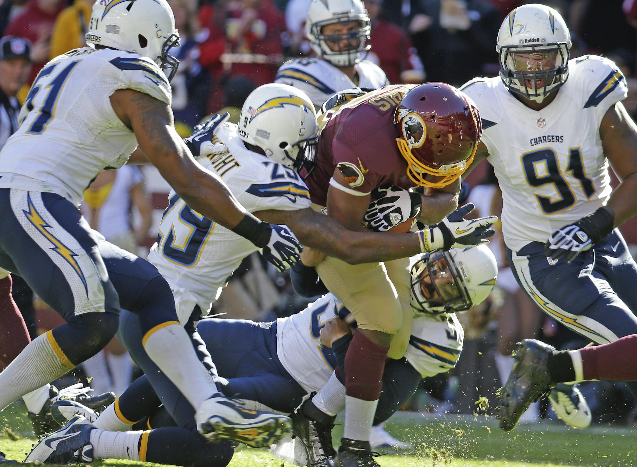 Washington Redskins running back Alfred Morris is stopped by San Diego Chargers cornerback Shareece Wright (29) and free safety Eric Weddle, bottom, after a 26-yard carry that setup a Washington touchdown during the first half of a NFL football game in Landover, Md., Sunday, Nov. 3, 2013. (AP Photo/Alex Brandon)