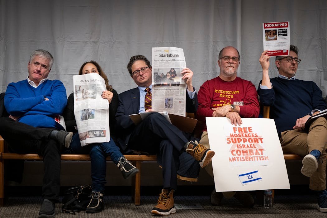 Local Jewish Community Relations Council Board Chairman Jon Parritz, on left, and others hold posters with the faces of those kidnapped by Hamas and newspapers as Minneapolis City Council members voted on a resolution calling for a ceasefire in Gaza and an end to U.S. military aid to Israel.