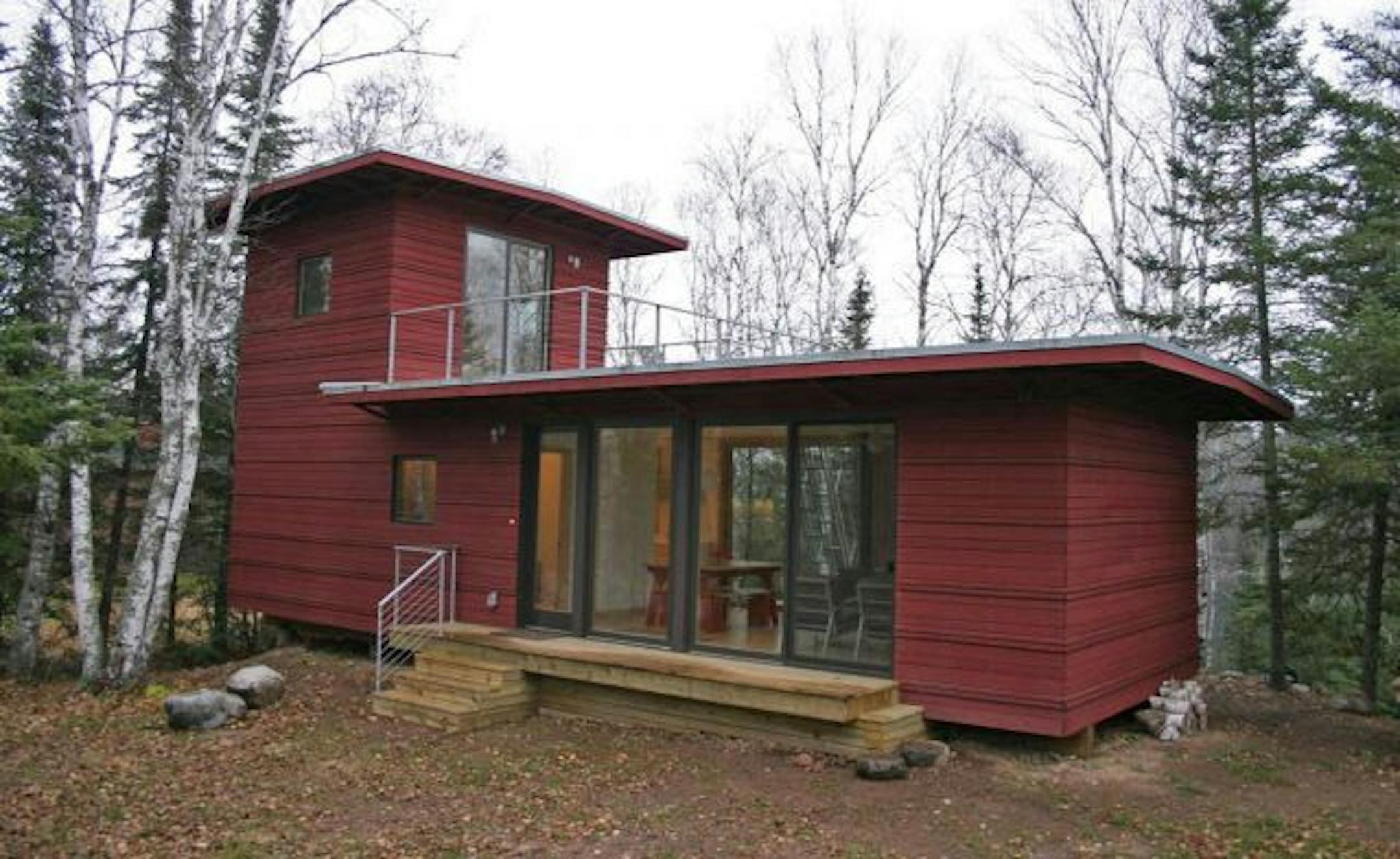The 800-square-foot modular cabin was built in a factory and assembled on-site. A steel ship's ladder leads to a rooftop deck and the second-floor bedroom.