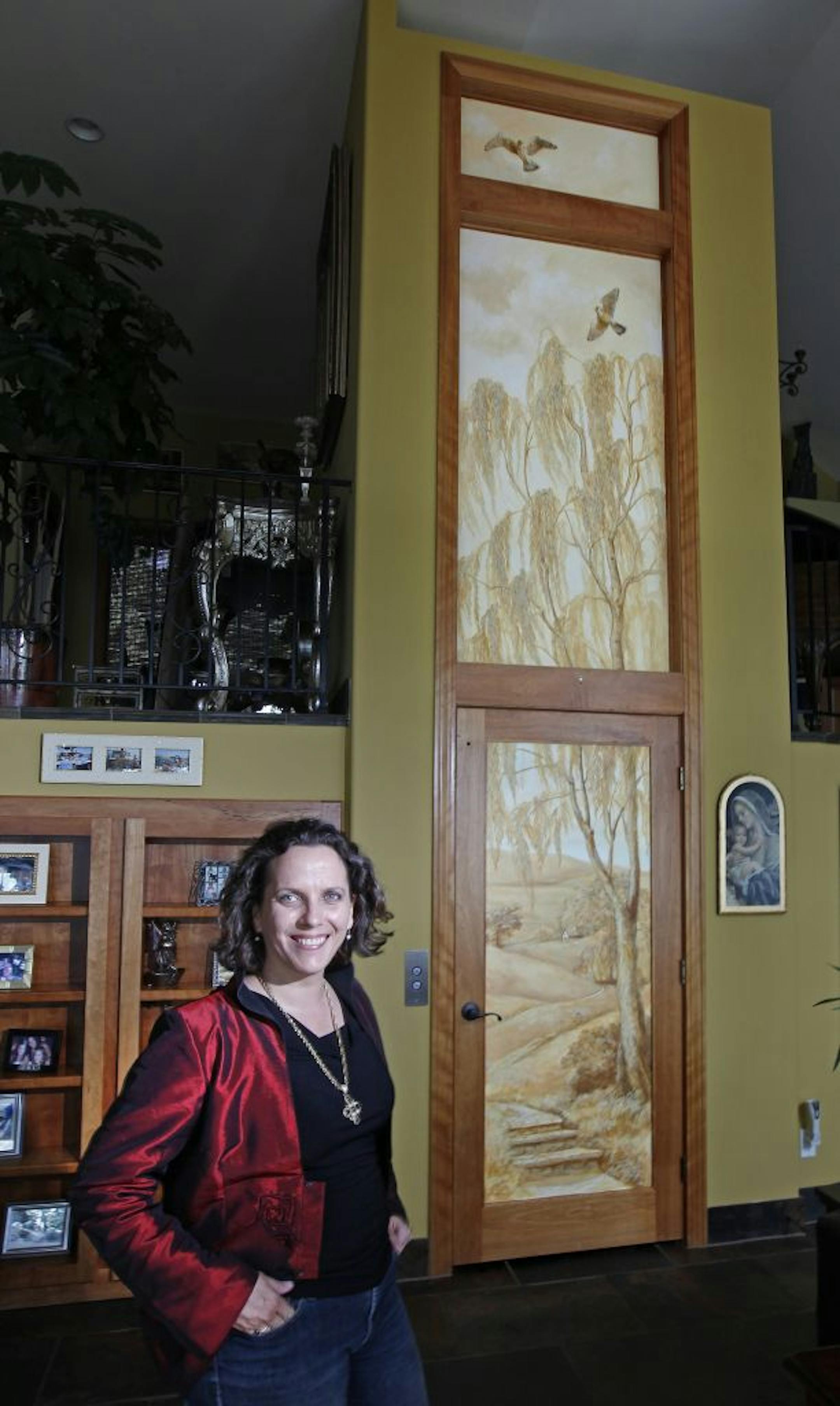 Tracie Thompson stood near a custom mural she painted on an elevator shaft of a client's Orono home.