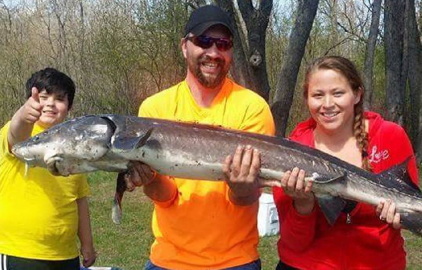 Hayden Magle (left), Jesse Smith and Sarah Warner, of Ramsey, display the 50-pound, 66-inch sturgeon caught from the bank of the St. Croix River in May using a worm. Garon Smith, who helped reel it in, took the photo.