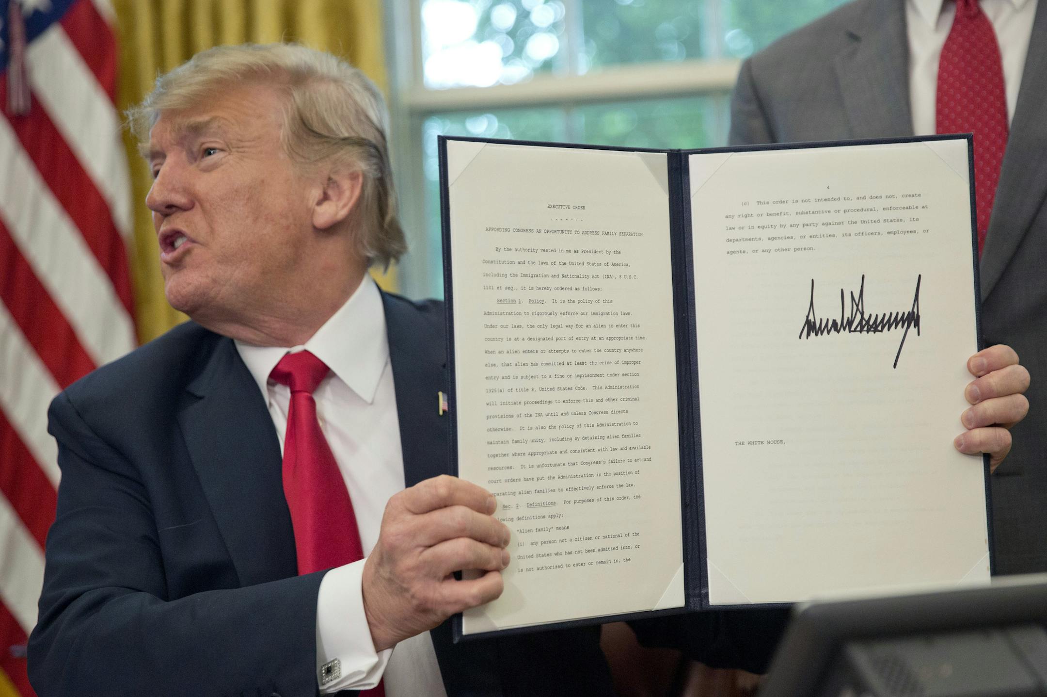 President Donald Trump holds up the executive order he signed to end family separations at the border, during an event in the Oval Office of the White House in Washington, Wednesday, June 20, 2018. (AP Photo/Pablo Martinez Monsivais)