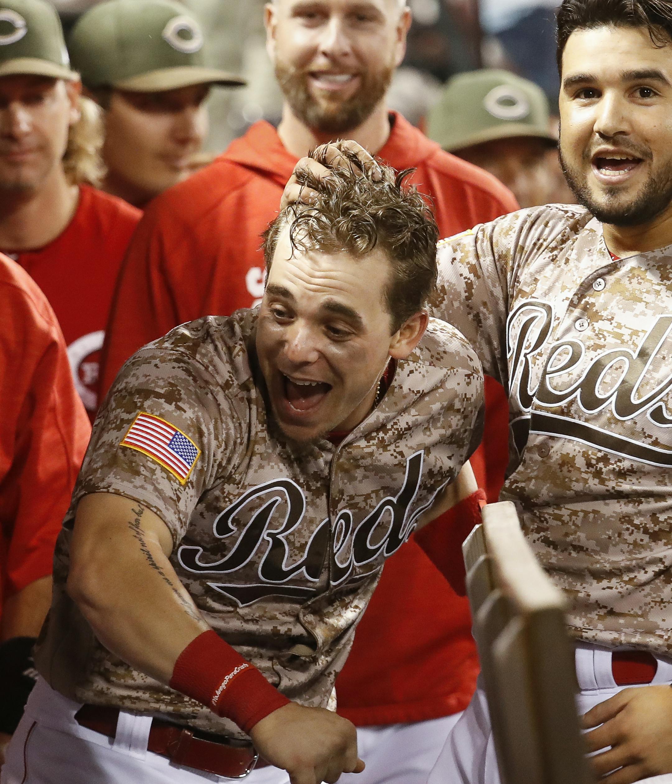 Cincinnati Reds' Scooter Gennett, center, celebrates in the dugout after hitting a two-run home run and his fourth overall in the eighth inning of a baseball game against the St. Louis Cardinals, Tuesday, June 6, 2017, in Cincinnati. The Reds won 13-1. (AP Photo/John Minchillo)